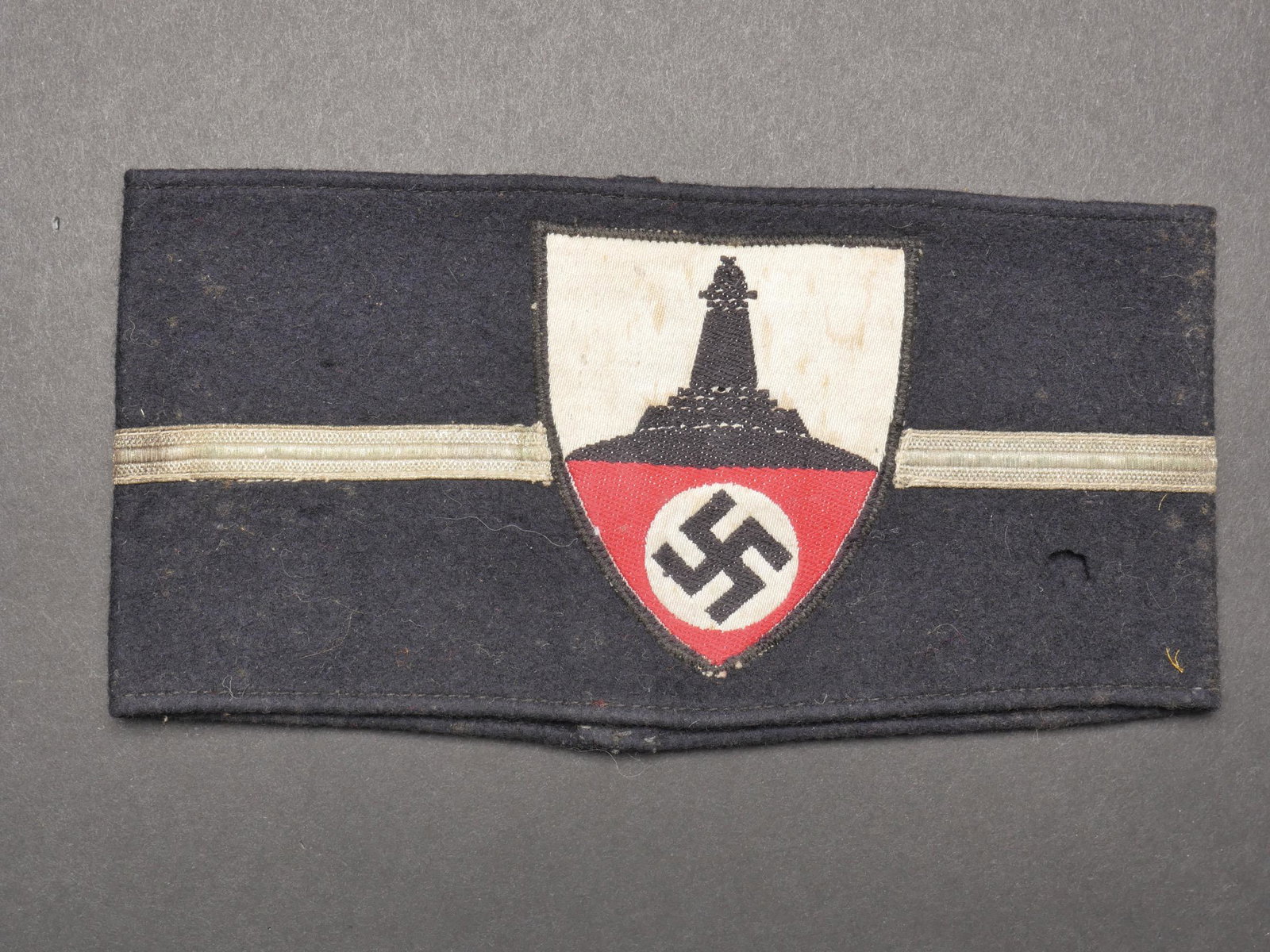 Brassard Kyffhauserbund. Kyffhauserbund armband.: Brassard Kyffhauserbund. Brassard en drap bleu marine. Insigne tisse et rapporte. Galon or au centre du brassard, correspondant au grade de Kameradschaftsfuhrer. Quelques trous de mite. Sans marquage 