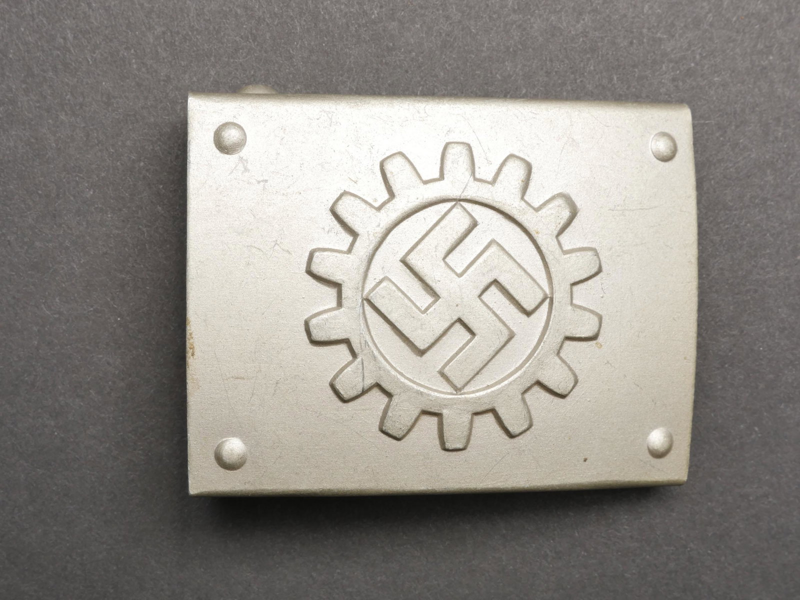 Boucle de ceinturon du DAF. DAF Belt Buckle.: Boucle de ceinturon du DAF. En aluminium. Insigne en relief. Fabrication RZM M4/27, correspondant au fabricant Overhoff et Co Ludenscheid. Boucle a deux ardillons presente. Etiquette RZM marquee Werks