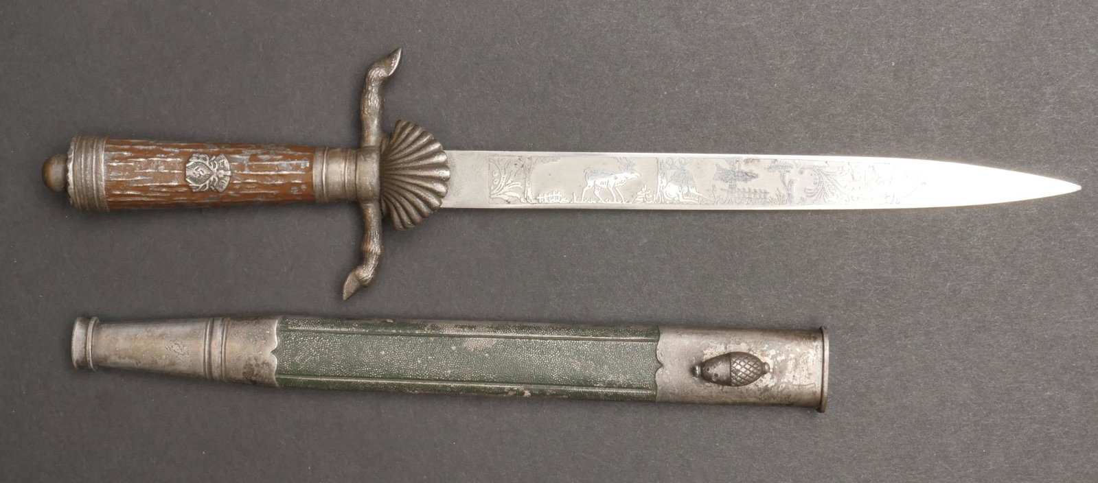 Miniature de dague DJ. Miniature of a DJ dagger.: Miniature d une dague de chasse DJ. Poignee en metal, peinture marron a 60%. Pommeau devissable. Insigne DJ visible sur le manche. Garde en S, representant des pattes de cerf. Coquille complete. Fourr