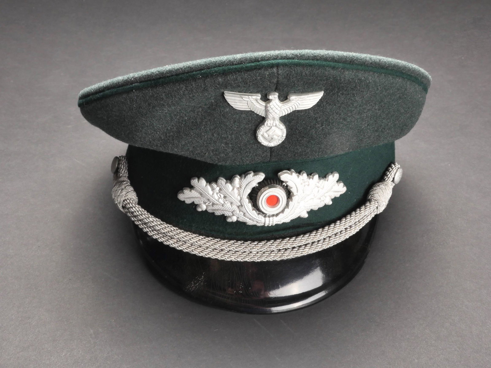 Casquette de forestier du Reich. Reich Forester s cap.: Casquette de forestier du Reich. En drap vert foret. Triple lisere vert fonce. Aigle, cocarde et feuilles de chene en metal. Les insignes n ont pas ete demontes afin de verifier les attaches. Fausse j