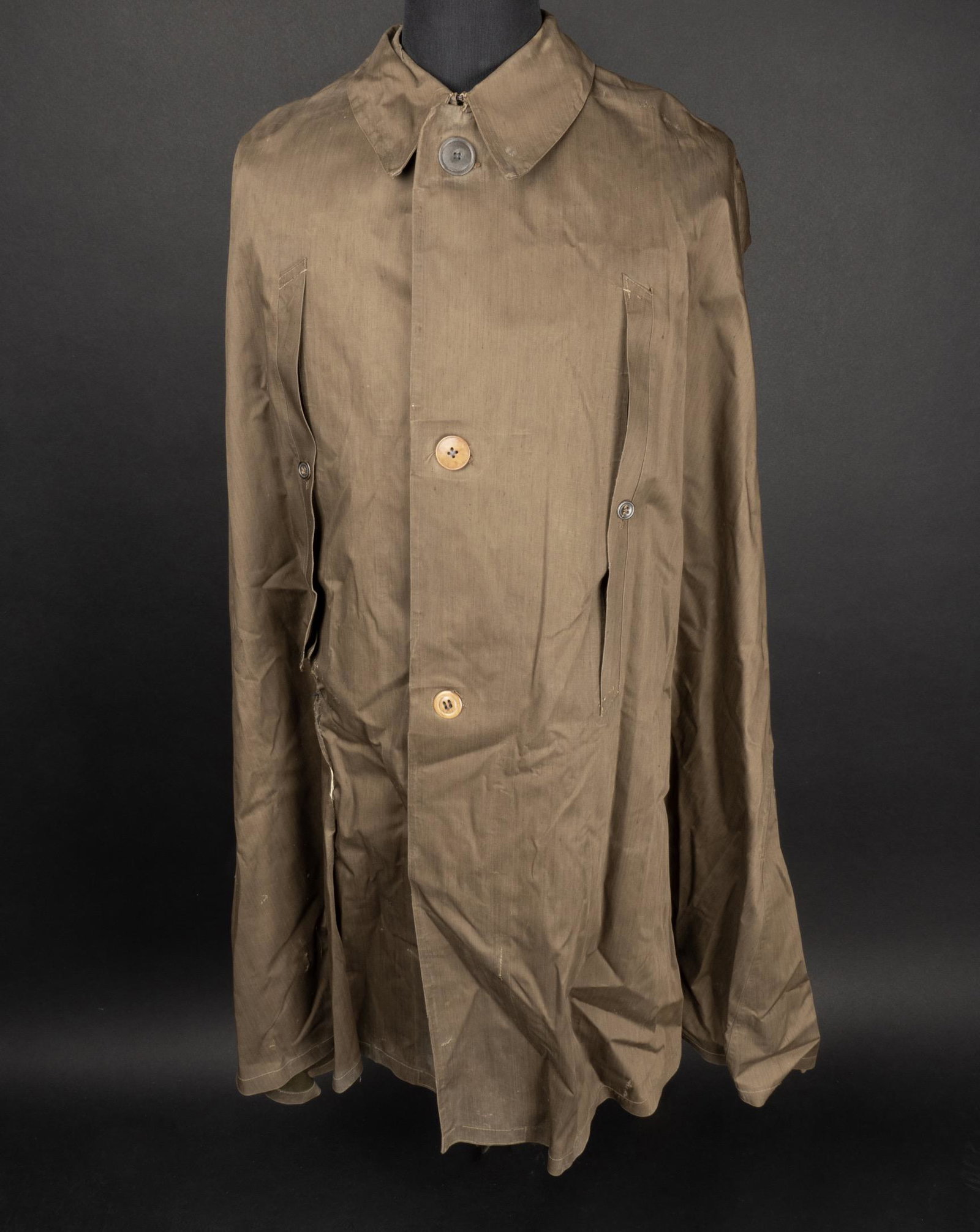 Cape de pluie HJ. HJ rain cape.: Cape de pluie Hitlerjugend. En toile impermeabilisee marron. Tous les boutons sont presents mais non homogene. Nombreux accrocs et reparations. Etiquette dans le col marquee HJ Regenumhang RZM Numero 