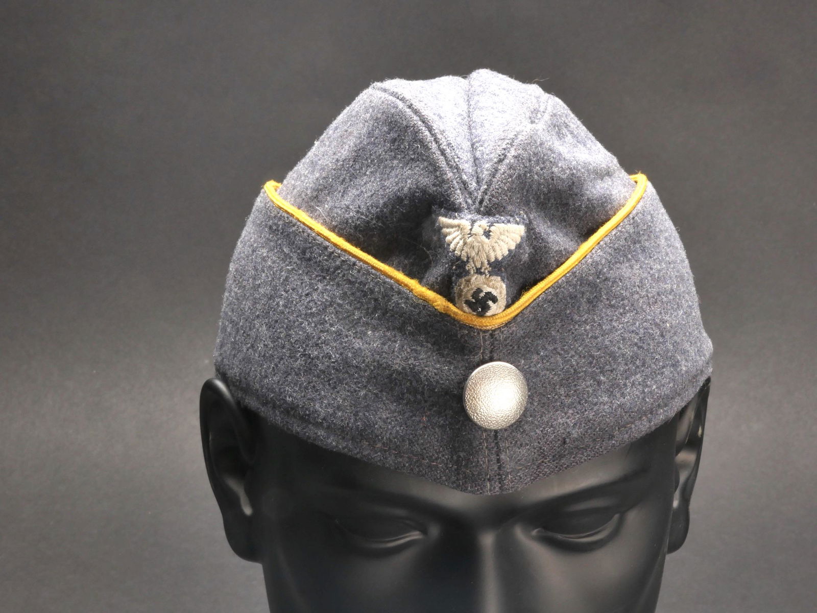 Calot NSFK. NSFK cap.: Calot NSFK. Un drap de laine gris/bleu. Lisere jaune d or faisant le tour de la coiffure. Un bouton grenele couleur argent. Aigle NSFK brode, monte main. Interieur double en tissu coton bleu marine, p