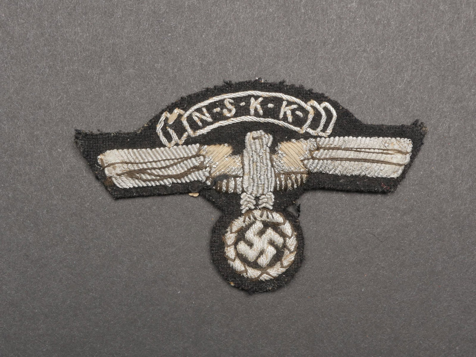 Insigne NSKK Belge. Belgian NSKK badge.: Insigne NSKK de fabrication belge. Modele pour officier en cannetille argent. Trace de colle au dos. Selon les informations du vendeur cette piece provient de la caserne de Vilvorde. A noter une certa