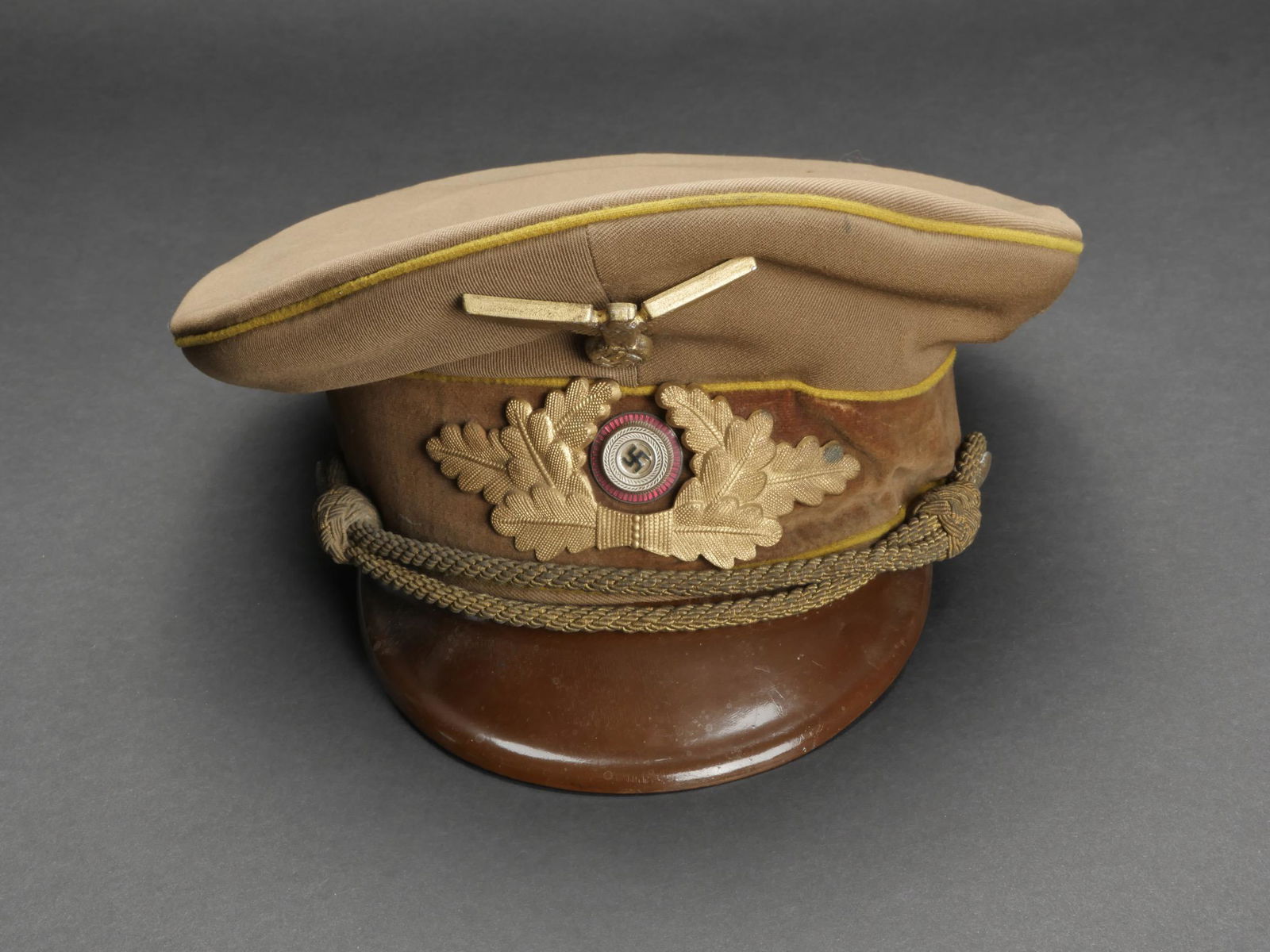 Casquette Reichsleitung. Reichsleitung cap.: Casquette Reichsleitung. En gabardine kaki. Triple lisere jaune du Reichsleitung. Insignes metalliques. Les insignes n ont pas ete demontes afin de verifier les attaches. Bandeau en velours jaune. Vis