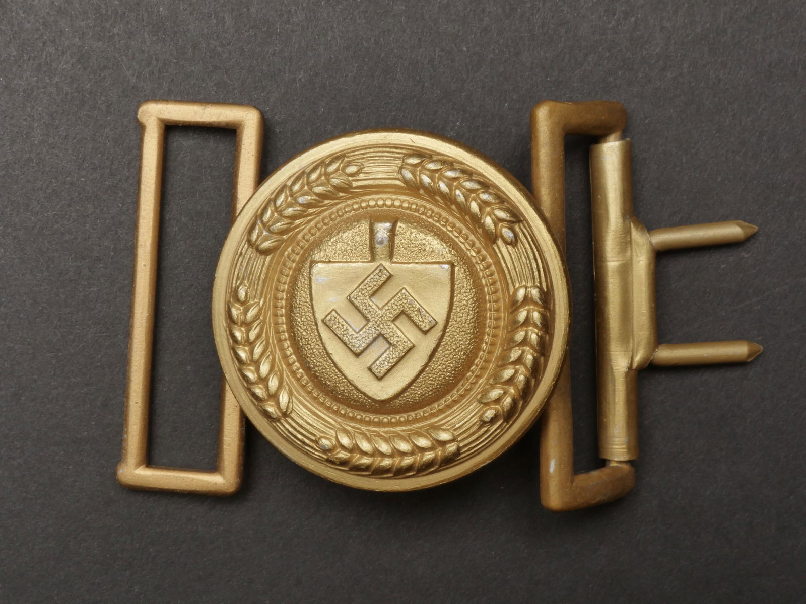 Boucle de ceinturon officier RAD. RAD officer belt buckle.: Boucle de ceinturon d officier RAD. En aluminium, dorure a 90%. Boucle a deux ardillons presente. Fabrication OLC Ges Gesch. A noter une certaine usure et patine de la piece. Etat II+. Belt buckle of