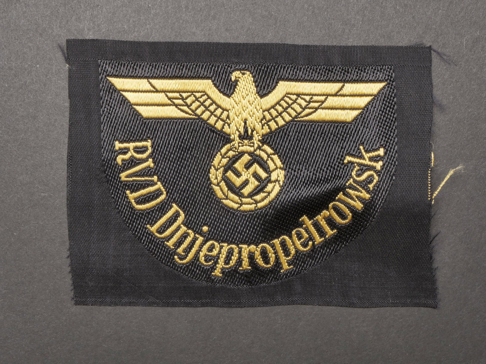 Insigne Reichsbahn. Badge Reichsbahn.: Insigne Reichsbahn. Modele tisses or sur fond noir. Marquages RVD Dnjepropetrowsk. Jamais monte. A noter une certaine usure et patine de la piece. Etat I-. Reichsbahn badge. Gold woven pattern on blac