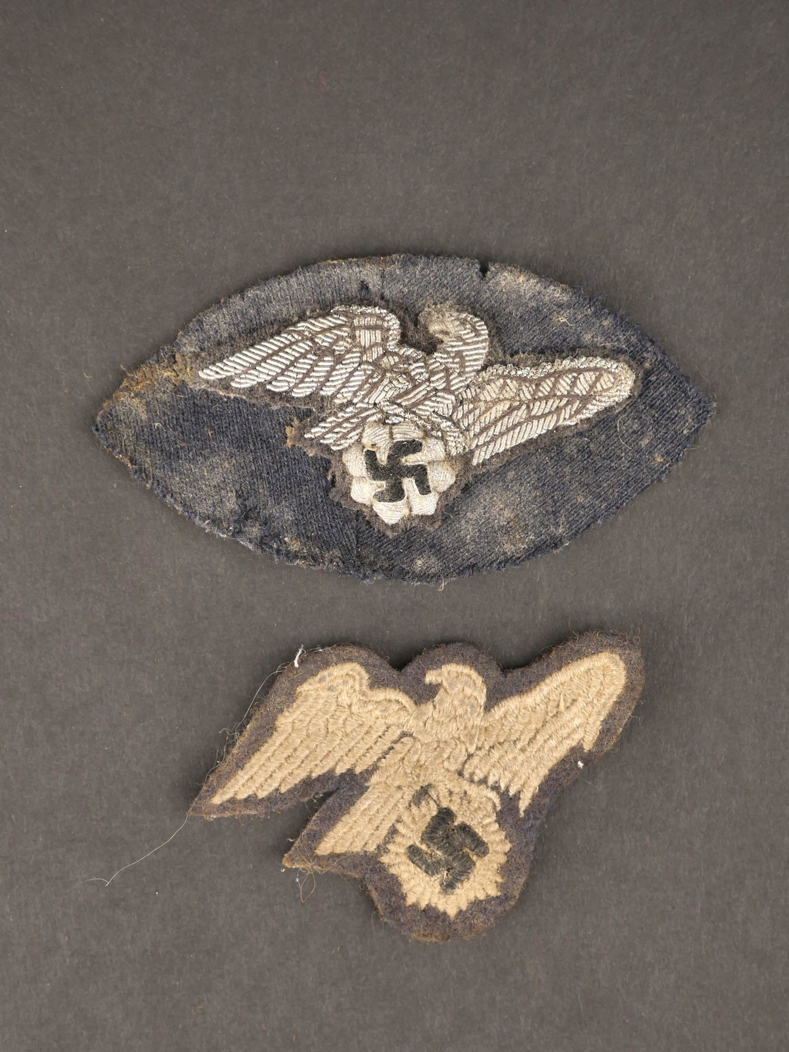 Insignes RLB. RLB insignia.: Insignes RLB. Comprenant un aigle, modele brode sur fond gris. Un aigle en cannetille argent bombe, sur fond bleu, fortement mite et tache. A noter une certaine usure et patine des pieces. Etat II+. R