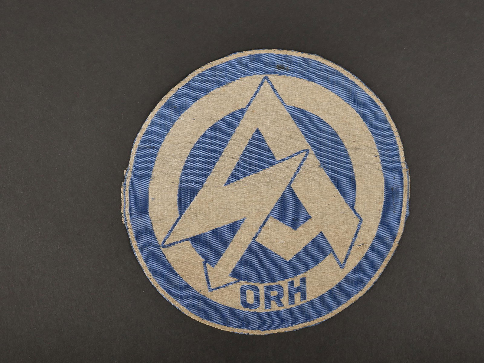 Insigne SA. SA insignia.: Insigne de maillot de sport SA. Modele tisse sur fond blanc, logo SA en tisse en fils bleu ciel, lettrage ORH. Jamais monte. Sans marquages visibles. Diametre 15 cm. Etiquette RZM absente. Trace de co