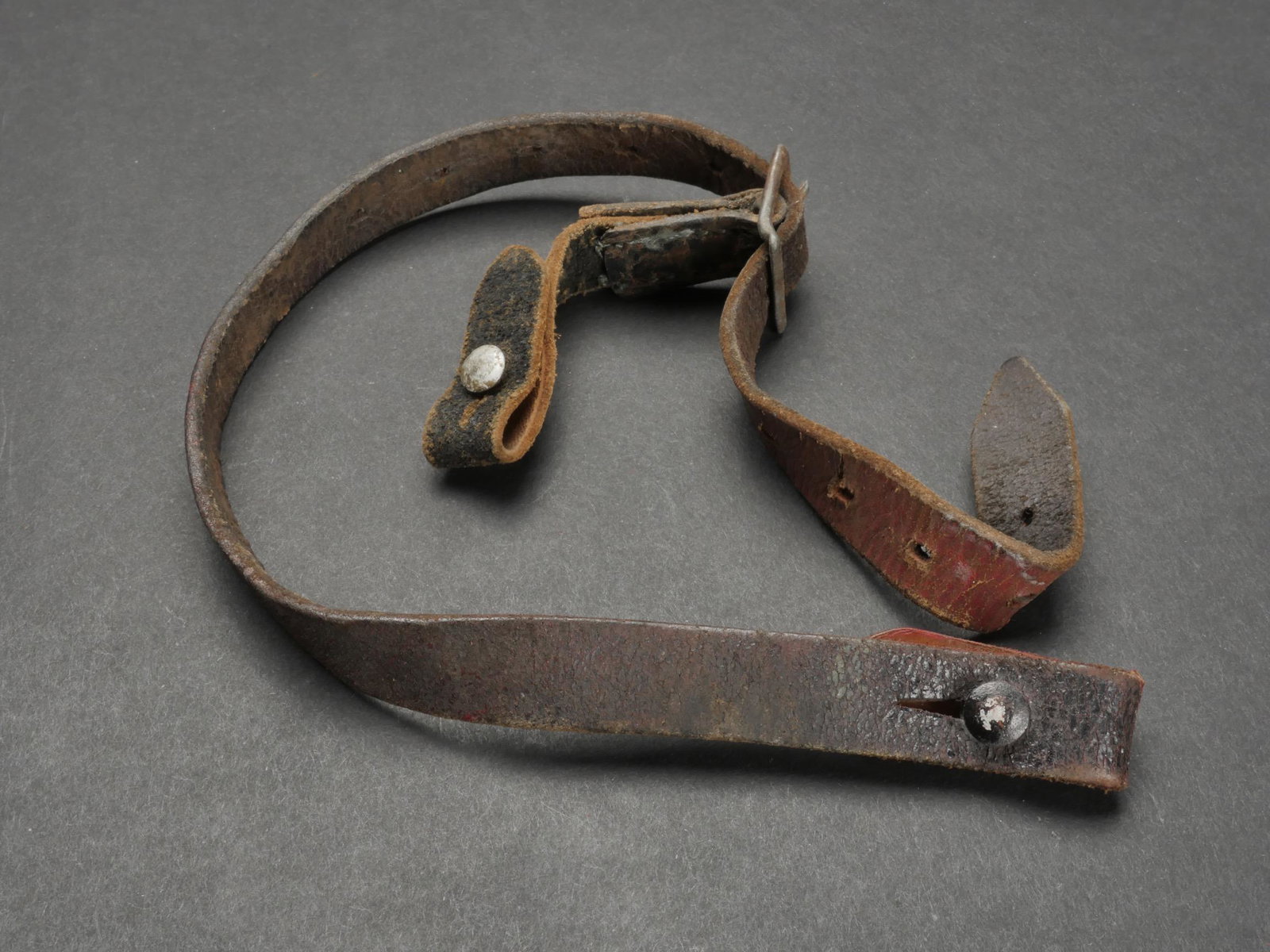 Jugulaire de casque. Helmet chinstrap.: Jugulaire de casque allemand. En cuir. Les tetons en metal sont presents. Boucle a ardillons complete. Treize trous de reglage. Sans marquages visibles. A noter une certaine usure et patine de la piec