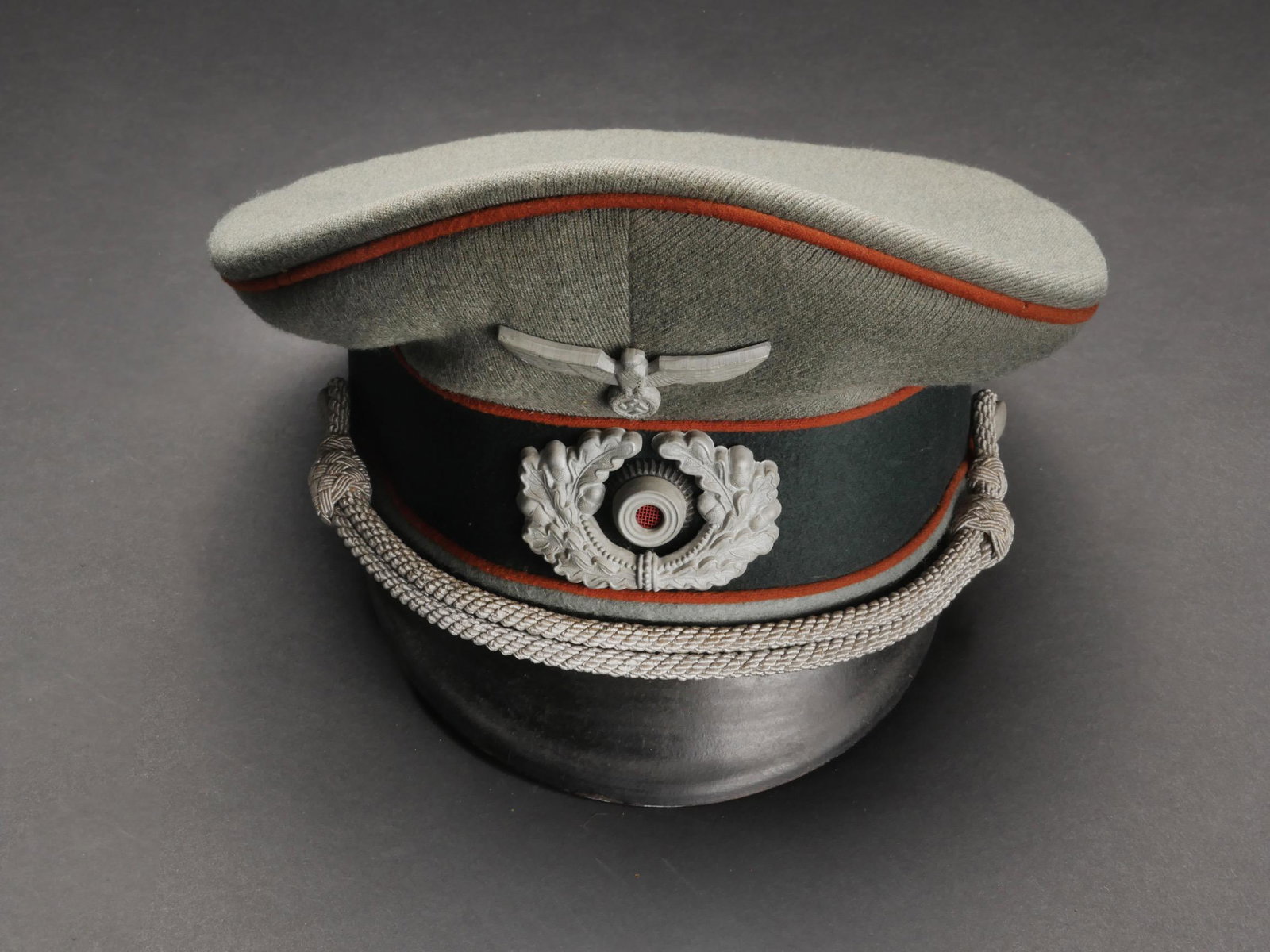 Casquette Feldgendarmerie. Feldgendarmerie cap: Casquette Feldgendarmerie. En drap Feldgrau. Triple lisere orange. Insignes metalliques. Les insignes n ont pas ete demontes afin de verifier les attaches. Fausse jugulaire d officier. Bandeau en drap