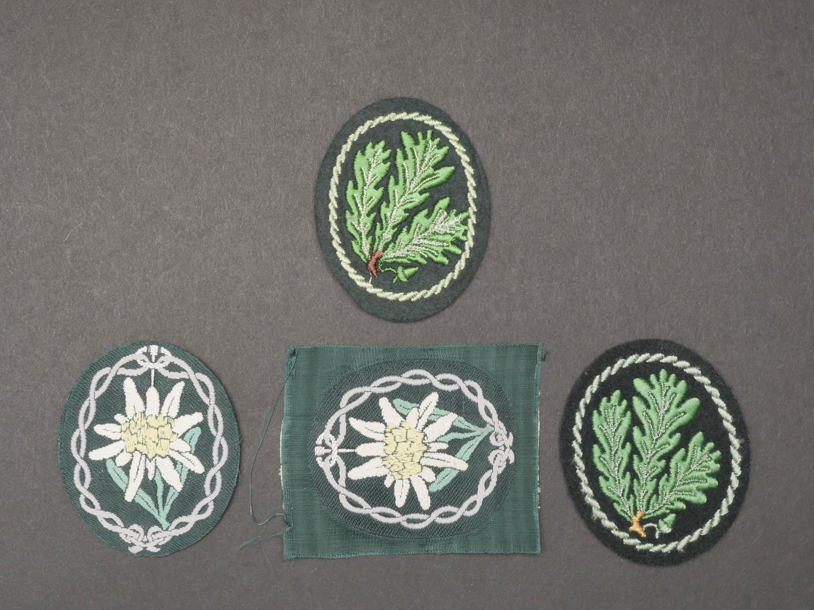 Insignes Gebirgsj ager. gebirgsj ager insignia.: Insignes Gebirgsj ager. Comprenant un edelweiss Bevo, jamais monte. Un edelweiss tisse, dos de la piece double en tissu noir, jamais monte. Deux insignes brodes de J ager. A noter une certaine usure e