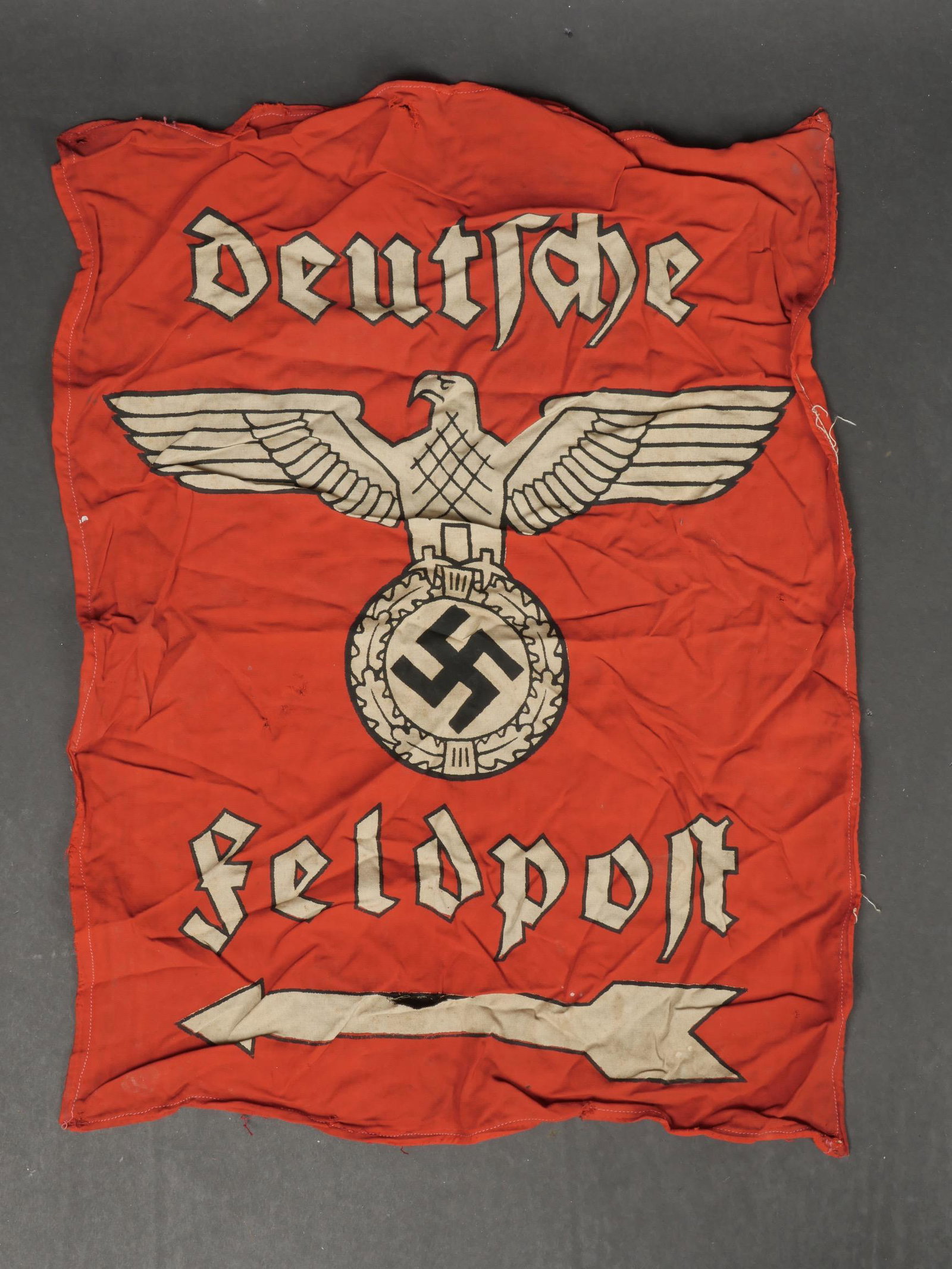 Drapeau Feldpost. Feldpost flag.: Drapeau feldpost. En tissu coton rouge, mono face. Imprime Deutsche Feldpost. Ce drapeau a ete decousu de sa structure en bois. Dimensions 44 x 57 cm. A noter une certaine usure et patine de la piece,