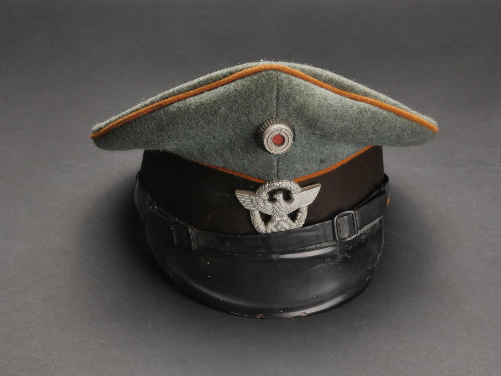 Casquette Polizei. Police cap.: Casquette de sous-officier Feldgendarmerie. En drap gris/vert. Triple lisere orange. Insignes metalliques. Les insignes n ont pas ete demontes afin de verifier les attaches. Fausse jugulaire en cuir.