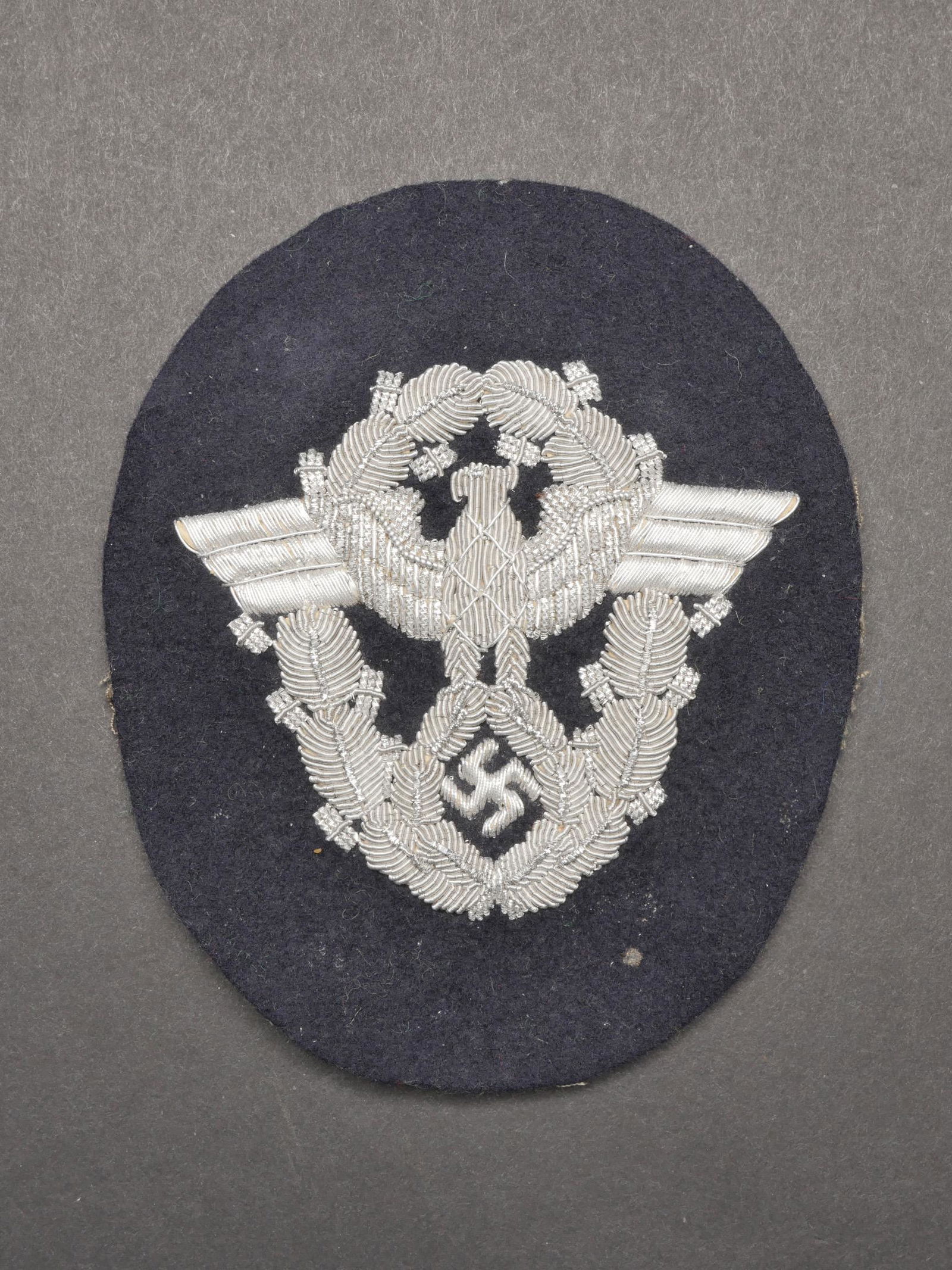 Aigle Polizei. Police eagle.: Aigle de manche Polizei. Modele en epaisse cannetille argent sur fond en drap bleu marine. Dos de la piece double en tissu gris. A noter une certaine usure et oxydation de la piece, ainsi que quelques
