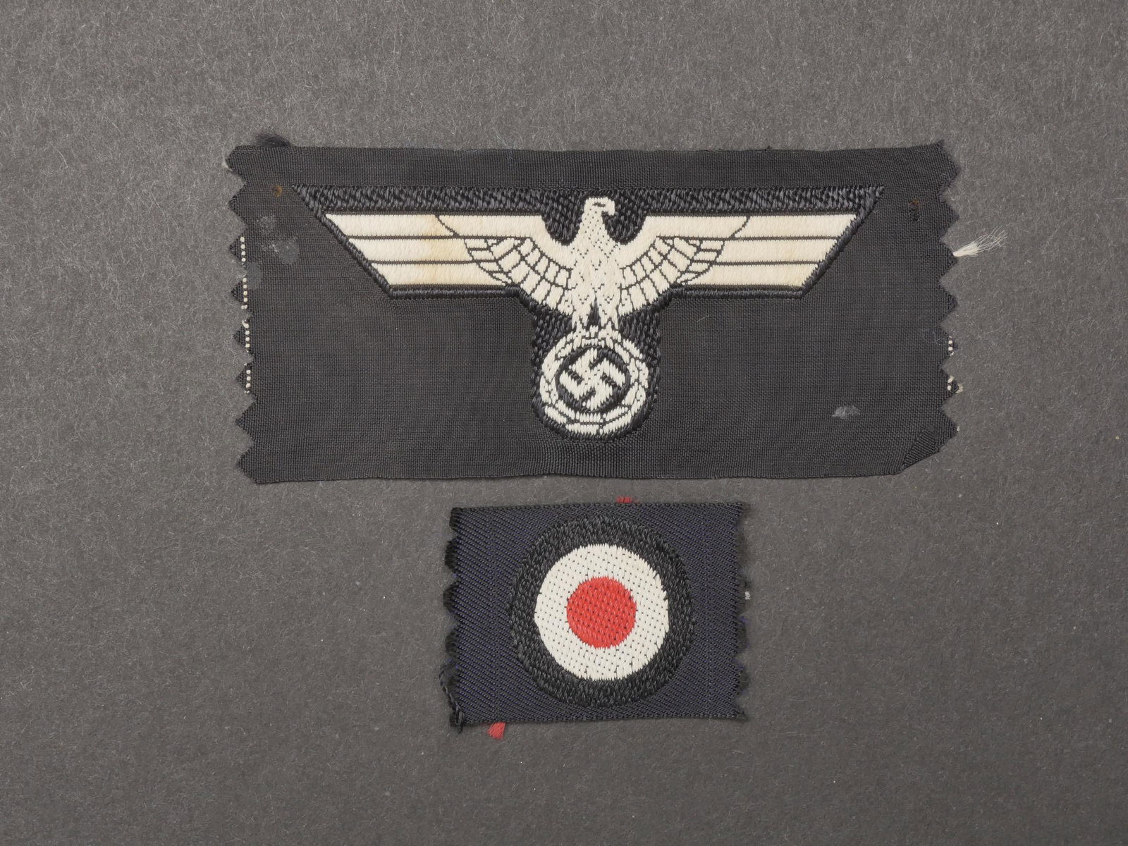 Insignes de calot Panzer. Panzer cap insignia.: Insignes de calot Panzer. Comprenant une cocarde Bevo, jamais monte. Un aigle de calot Bevo, jamais monte ni decoupe. Traces de colle au dos. A noter une certaine usure et patine des pieces. Ensemble 
