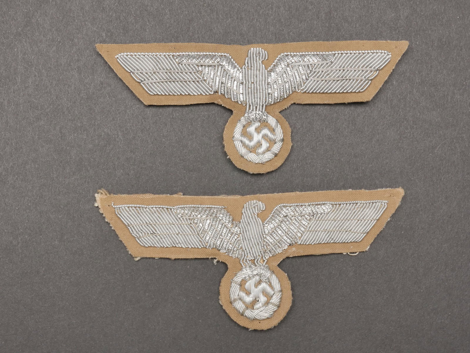 Aigles tropicaux Heer. Tropical eagles Heer.: Aigles tropicaux de la Heer. Comprenant deux aigles pour officier en cannetille argent, montes sur un fond en tissu couleur beige. Dos des pieces double en tissu blanc. Jamais montes. A noter une lege