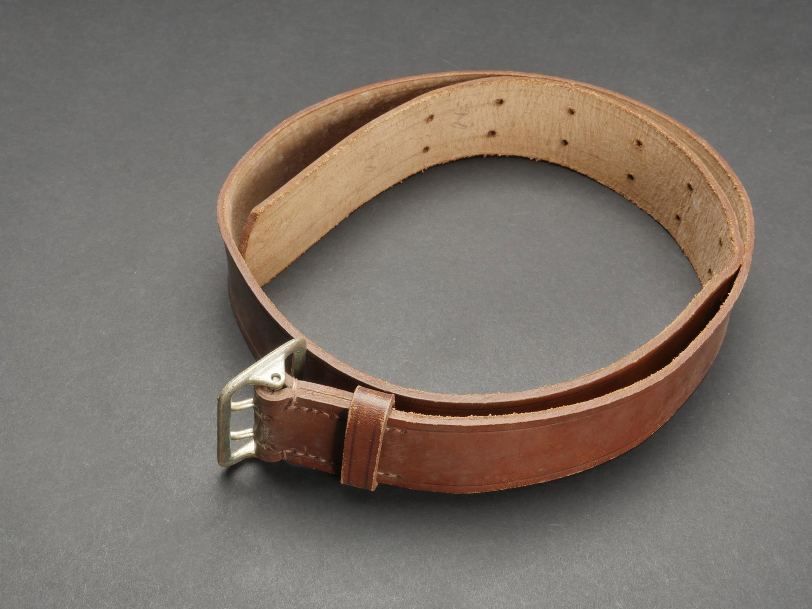 Ceinturon d officier LW. Officer s belt LW.: Ceinturon d officier de la Luftwaffe. En cuir marron. Boucle a deux ardillons en metal grenele. Un passant de ceinturon present. Sans marquages visibles. Taille 115. Indication nominative illisible au