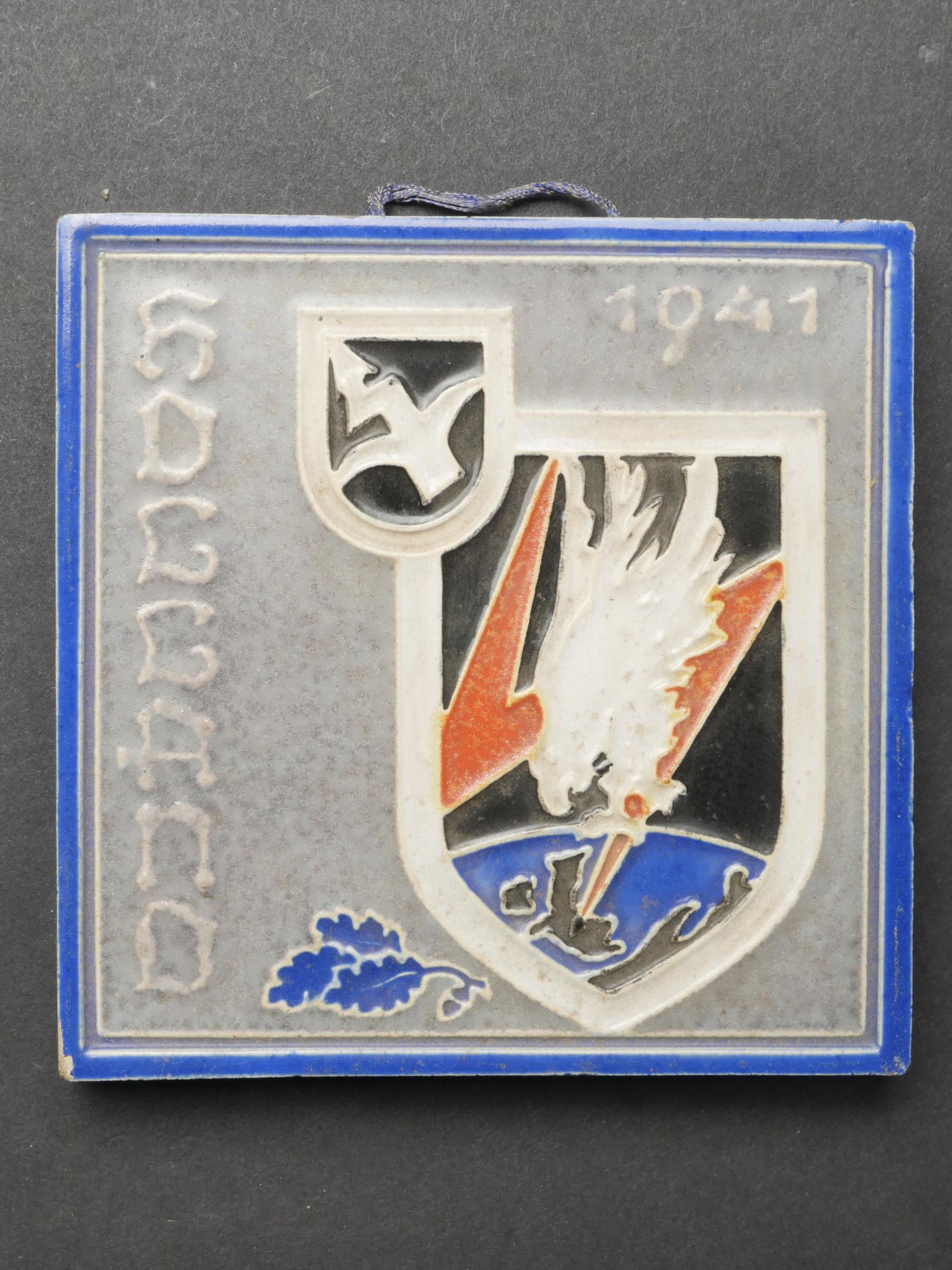 Carreau en faience LW. Earthenware tile LW.: Carreau en faience du Nachtjagdgeschwader 5. En faience peinte, bel insigne du Nachtjagdgeschwader 5, et mentions Holland 1941. Systeme d accroche au dos present. Marquages en flamand Westraven Utrech
