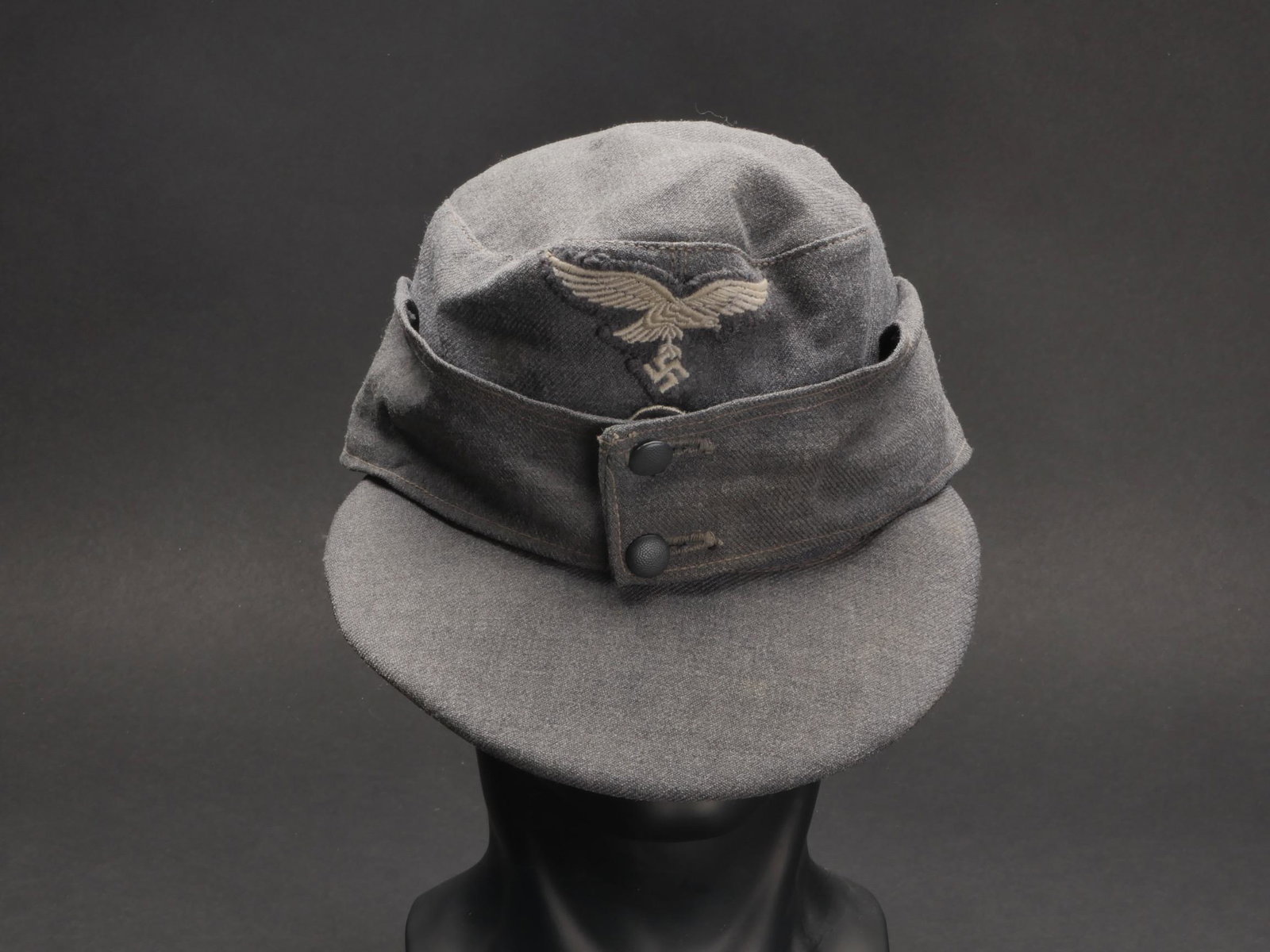 Casquette M-43 LW. M-43 LW cap.: Casquette M-43 de la Luftwaffe. En tissu gris/bleu fortement passe par le soleil. Aigle de la Luftwaffe du second type, monte main. Deux boutons greneles en couleur d origine fermant le rabat. Interie