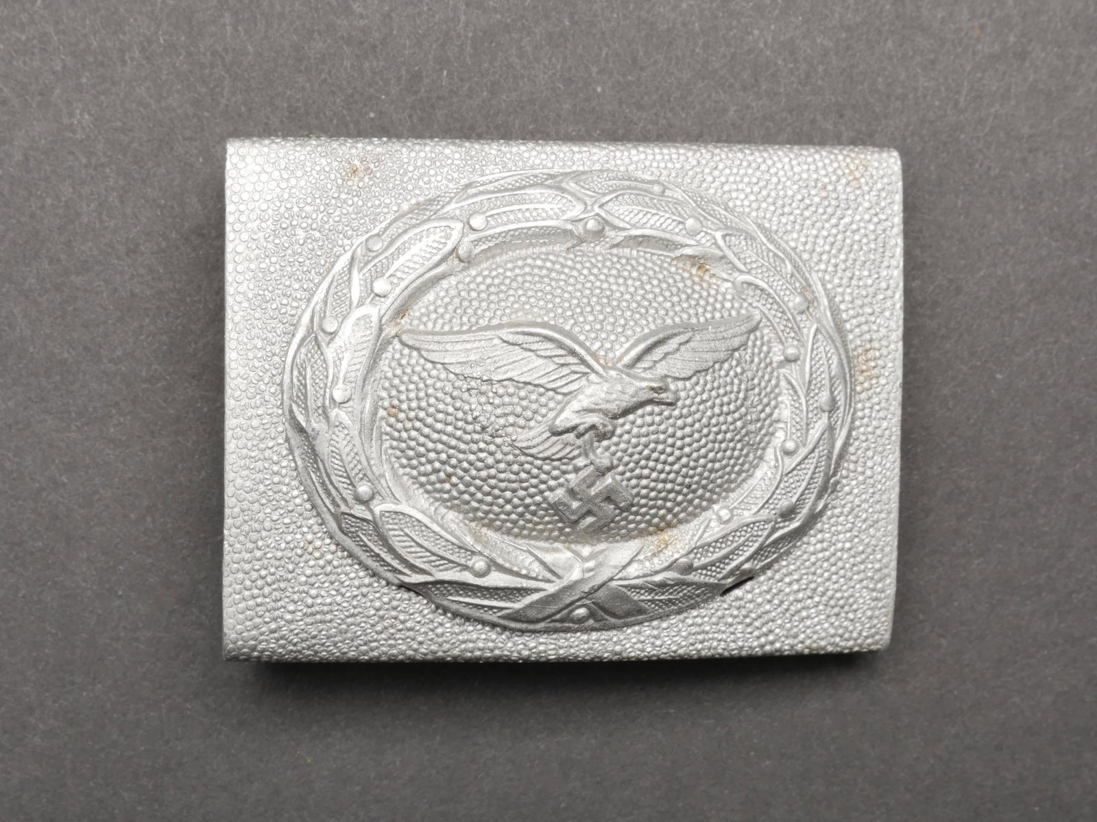 Boucle de ceinturon Luftwaffe. Luftwaffe belt buckle.: Boucle de ceinturon Luftwaffe. En aluminium grenele. Fabrication en deux parties. Couleur argent a 70%. Boucle a deux ardillons complete. Sans marquages visibles. A noter une certaine usure et patine 