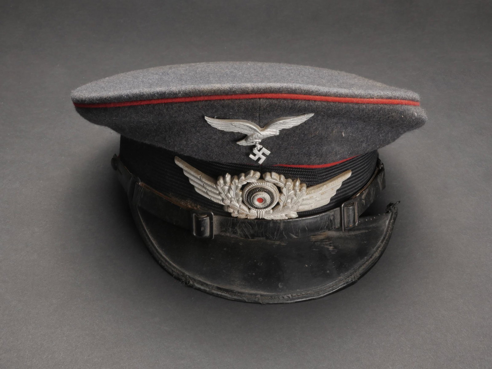 Casquette Flak. Flak cap.: Casquette de sous-officier de la Flak. En drap gris/bleu. Triple lisere rouge de la Flak. Insignes metalliques. Les insignes n ont pas ete demontes afin de verifier les attaches. Bandeau en mohair noi