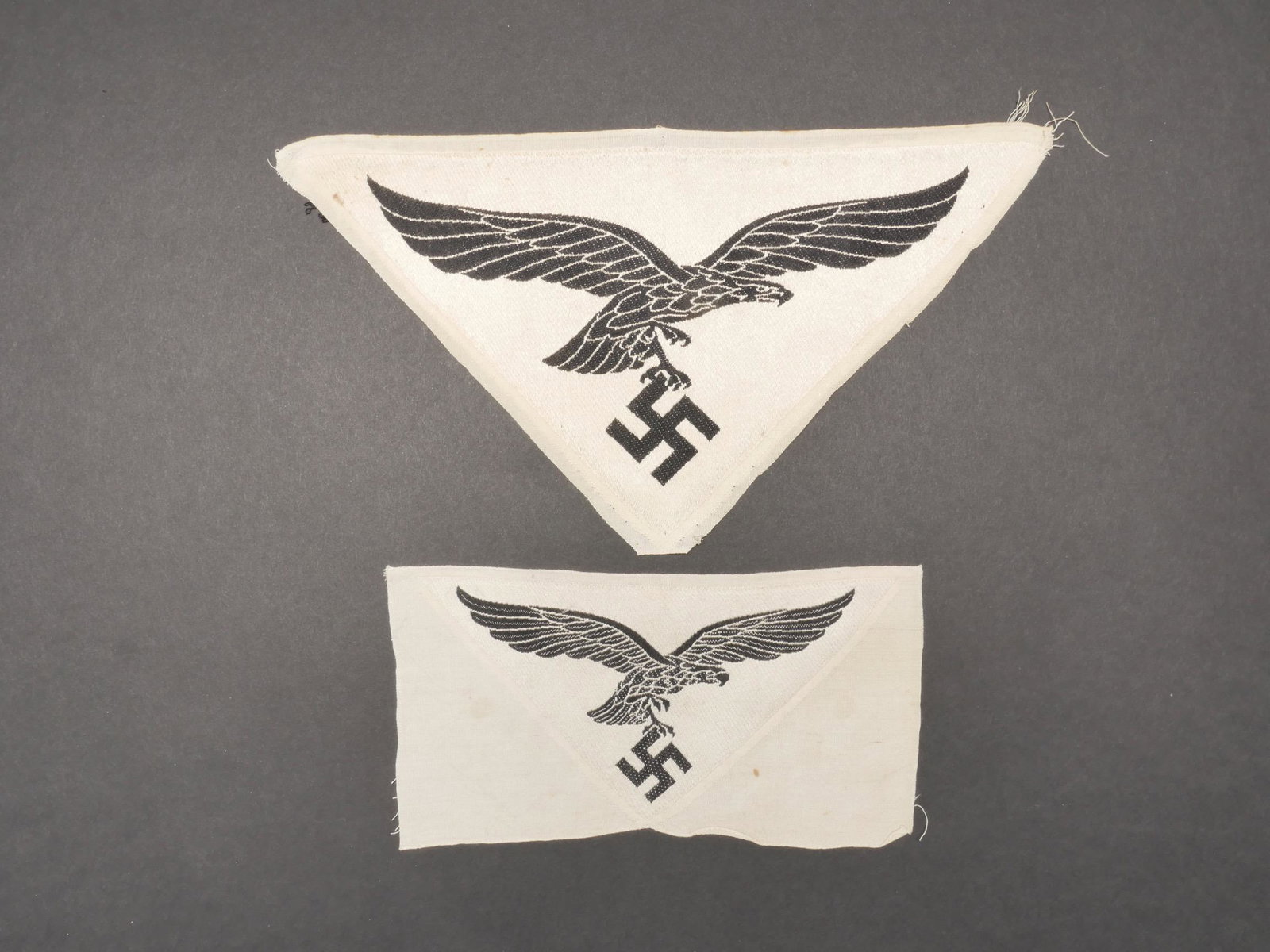 Insignes de maillots de sport LW. LW sports shirt insignia.: Insignes de maillots de sport de la Luftwaffe. Comprenant un grand modele d insigne brode sur fond blanc, jamais monte. Un petit modele d insigne de la Luftwaffe, sur fond blanc, jamais monte. A noter