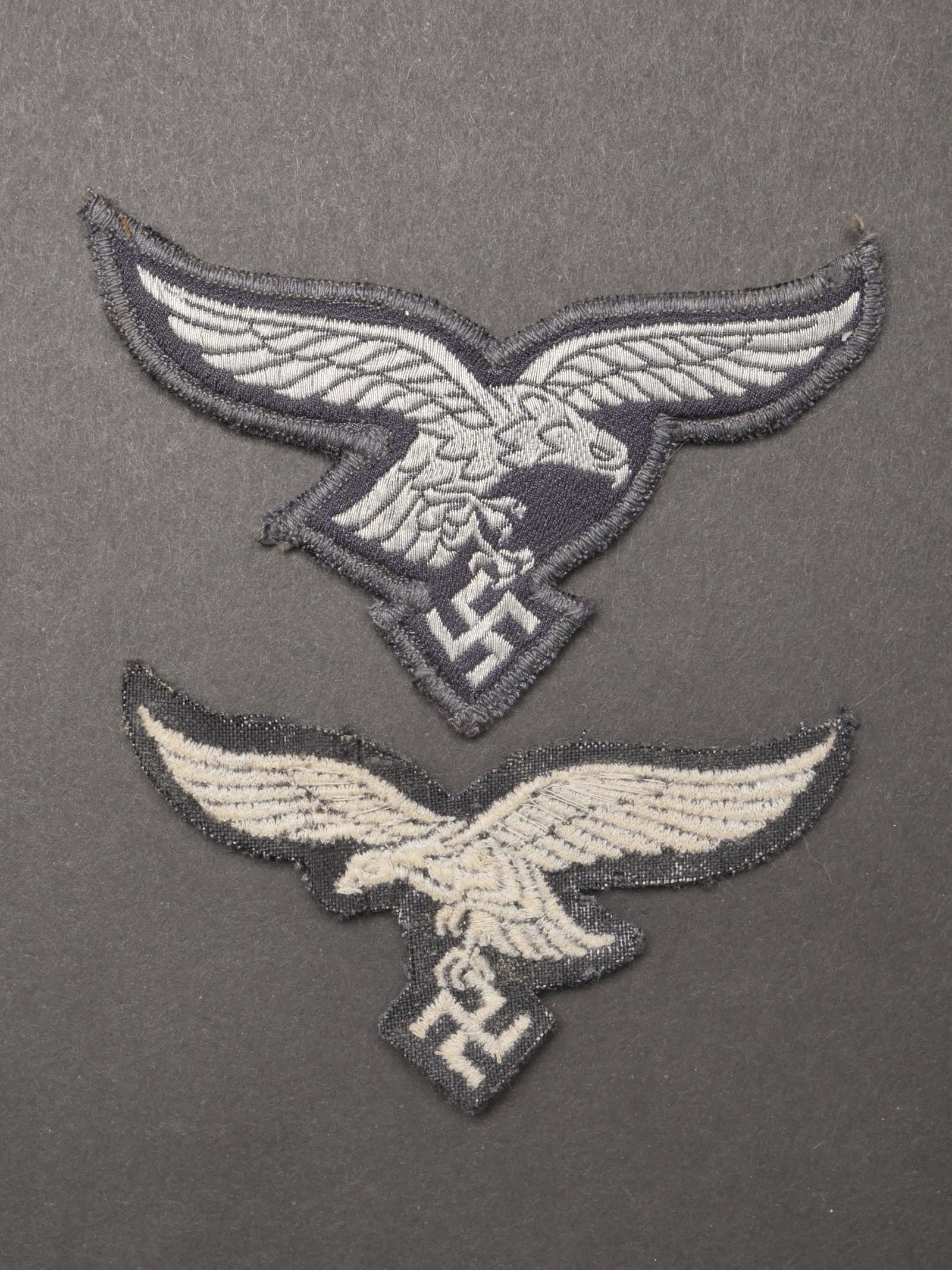 Aigles de poitrine Luftwaffe. Luftwaffe chest eagles.: Aigles de poitrine Luftwaffe. Comprenant un aigle de poitrine brode sur fond en drap gris/bleu, jamais monte. Un aigle de poitrine tisse sur fond en drap gris/bleu, bordures ourlets. Dos de la piece d