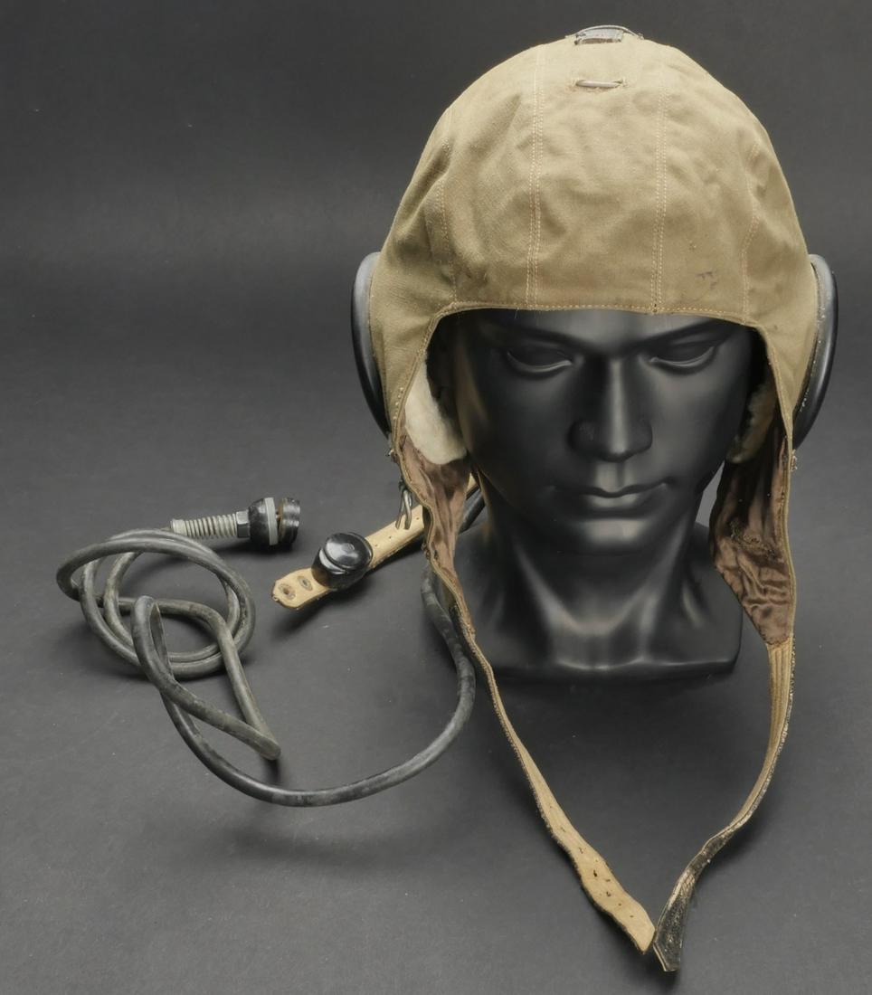 Bonnet de pilote LW. LW pilot s cap.: Bonnet de pilote de la Luftwaffe. En toile kaki. Les proteges ecouteurs sont en bakelite noire ovale et doubles de cuir et de fausse fourrure. Interieur double en satinette marron. Etiquette du fabric