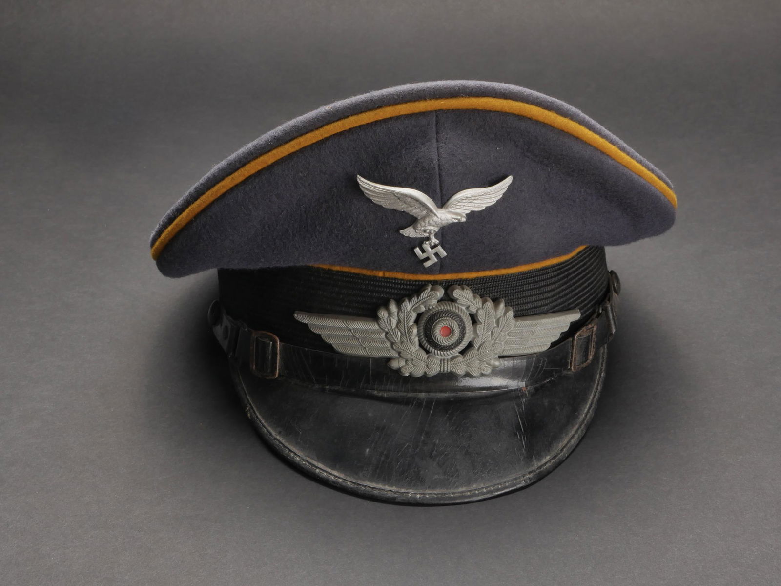 Casquette LW. LW cap.: Casquette de sous-officier du personnel volant ou parachutiste de la Luftwaffe. En drap gris/bleu. Triple lisere jaune du personnel volant ou parachutiste. Insignes metalliques. Les insignes n ont pas
