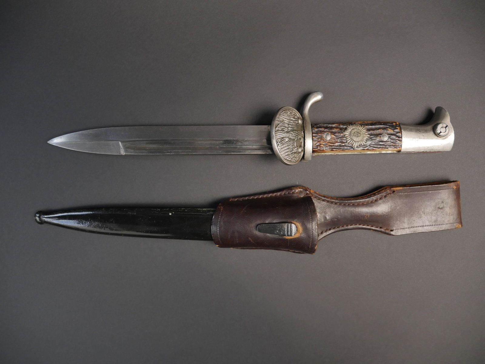 Baionnette allemande. German bayonet.: Baionnette allemande. Garniture en metal nickele. Plaquettes en fausse corne, maintenues par deux rivets. Insigne marque Suum Cuique. Garde orne d un aigle. Belle lame presentant une certaine usure et