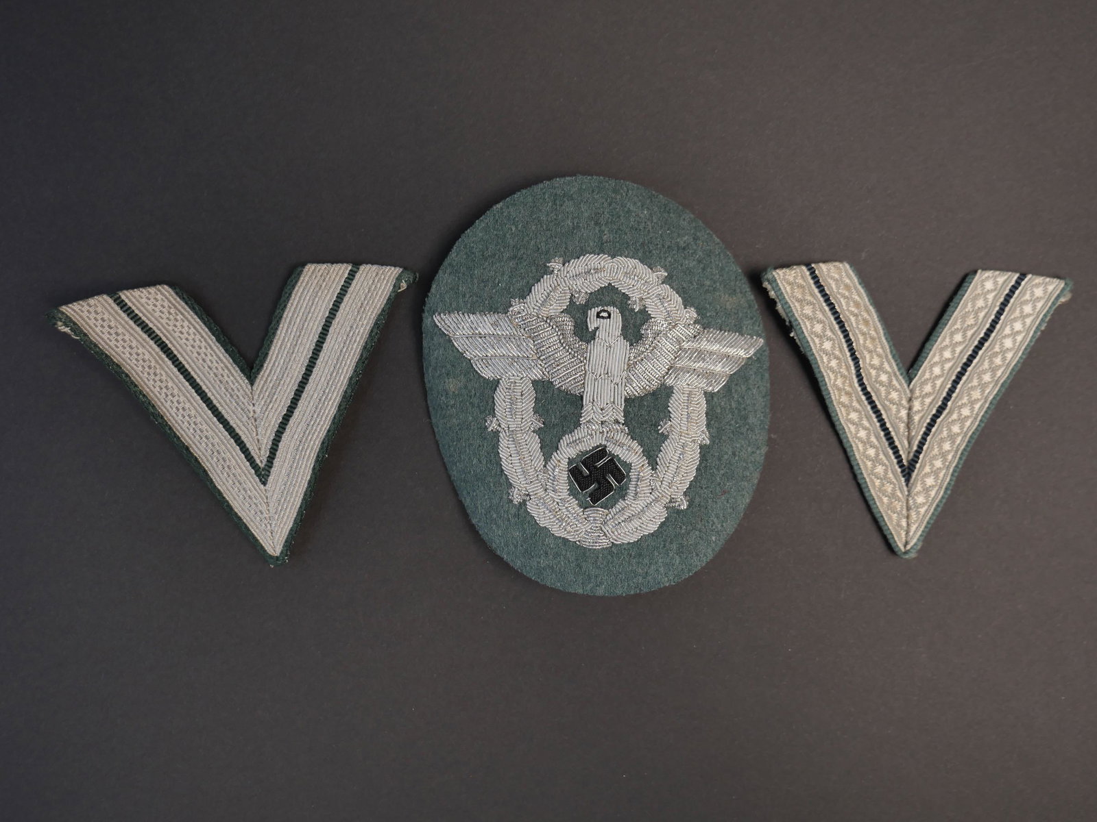 Insigne Polizei. German police insignia.: Insigne Polizei. Aigle de manche d officier en cannetille argent sur fond gris/vert. Traces de colle au dos. Deux grades de manche troupe. A noter une certaine usure et patine des pieces. Etat II+. Po