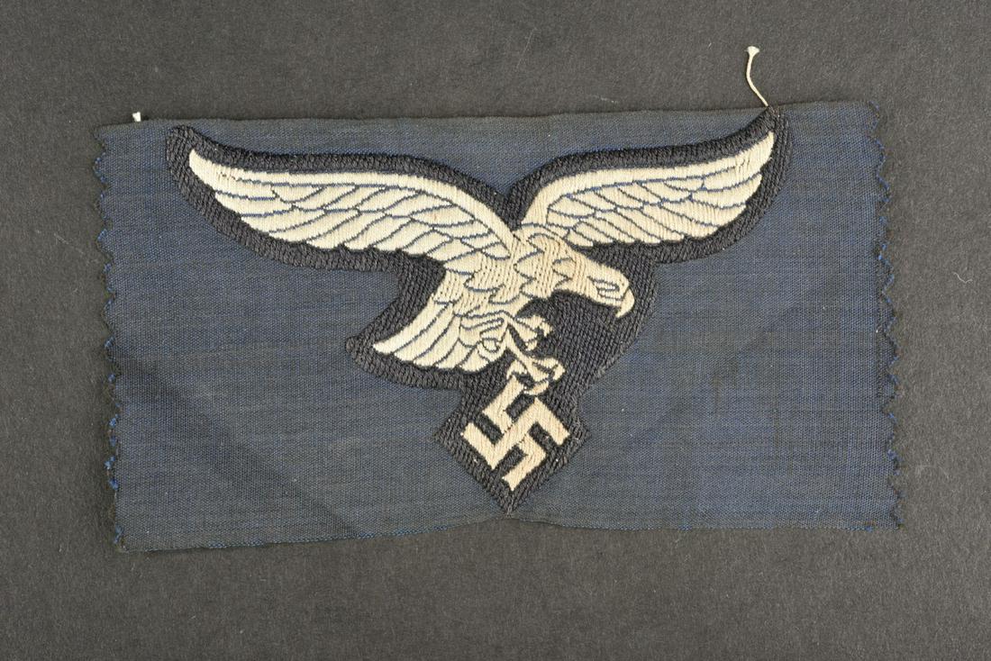 Aigle de poitrine LW. LW chest eagle.: Aigle de poitrine de la Luftwaffe. Aigle du premier type tisse sur fond bleu marine. Jamais monte. A noter une legere usure et patine de la piece. Etat I+. Luftwaffe chest eagle. First type eagle wove