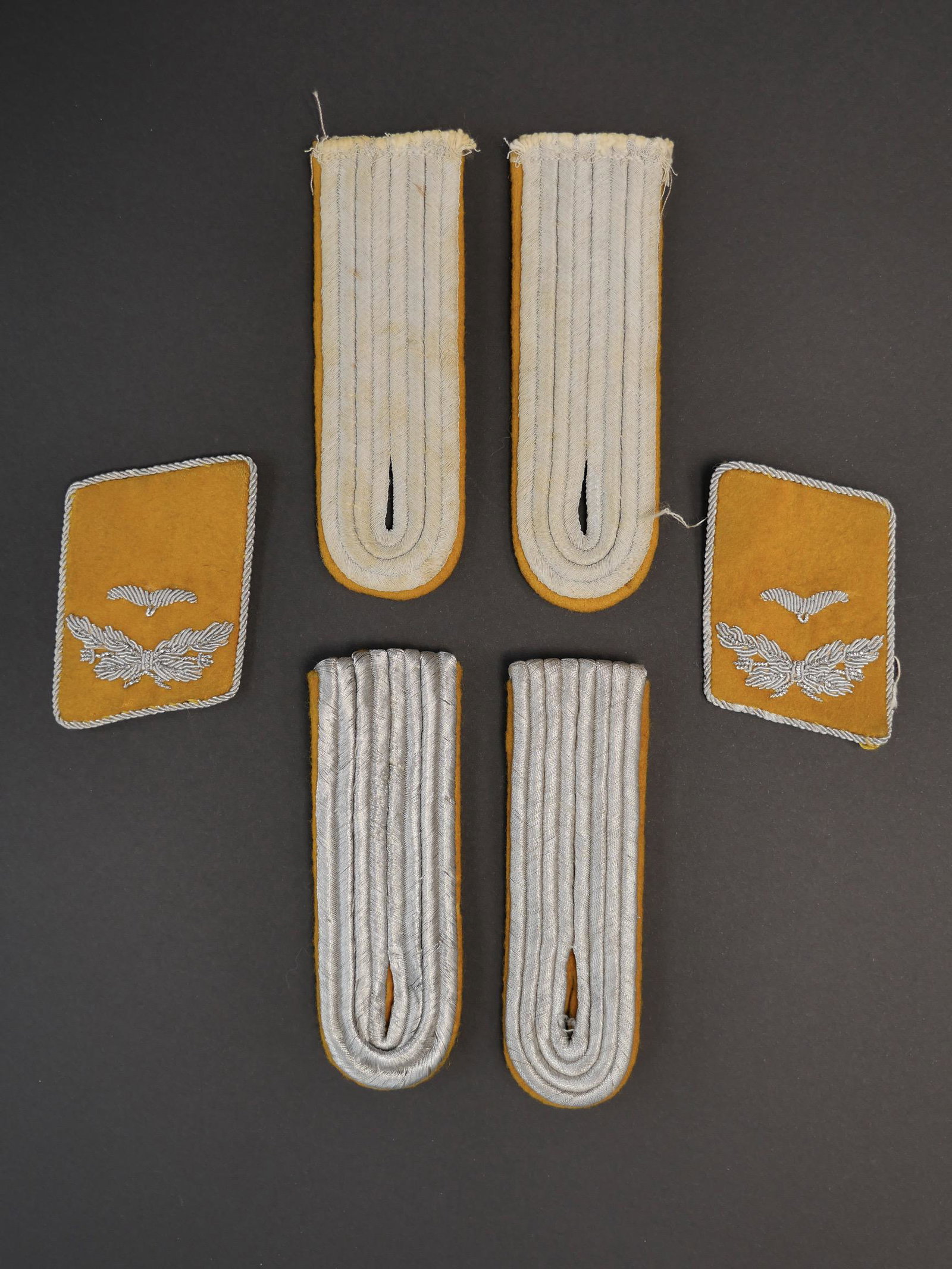 Insignes LW. Luftwaffe insignia.: Ensemble d insigne de la Luftwaffe. Comprenant deux paires homogene de pattes d epaule au grade de Leutnant, lisere jaune du personnel volant ou parachutiste. Une paire homogene de patte de col de Leu