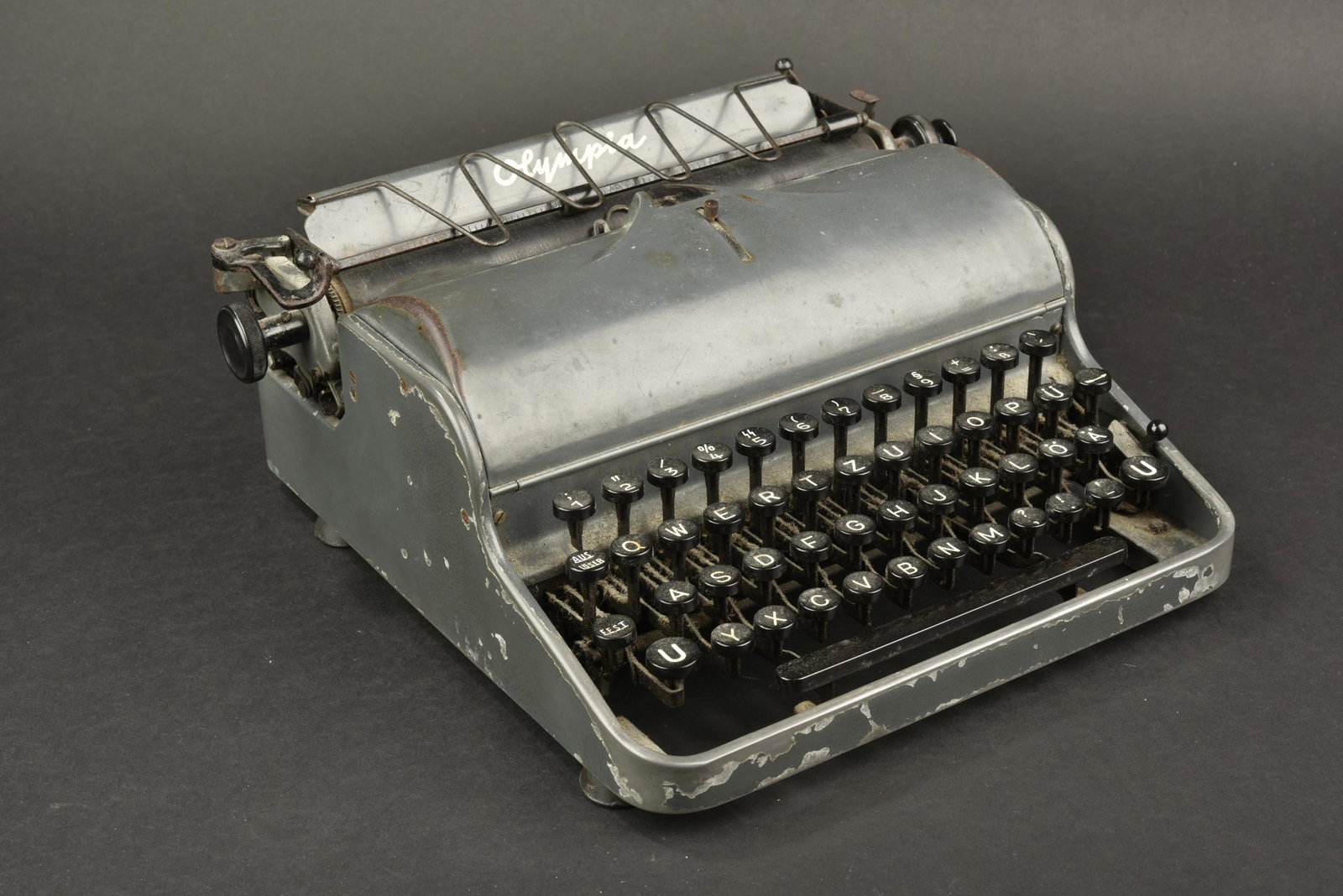 Machine a ecrire SS. SS Typewriter.: Machine a ecrire SS. En metal, toutes les pieces mobiles sont fonctionnelles. Peinture grise a 80%. Fabrication Olympia. Ruban encreur sec. Touche numero 5 disposant des runes de la Waffen SS. A noter