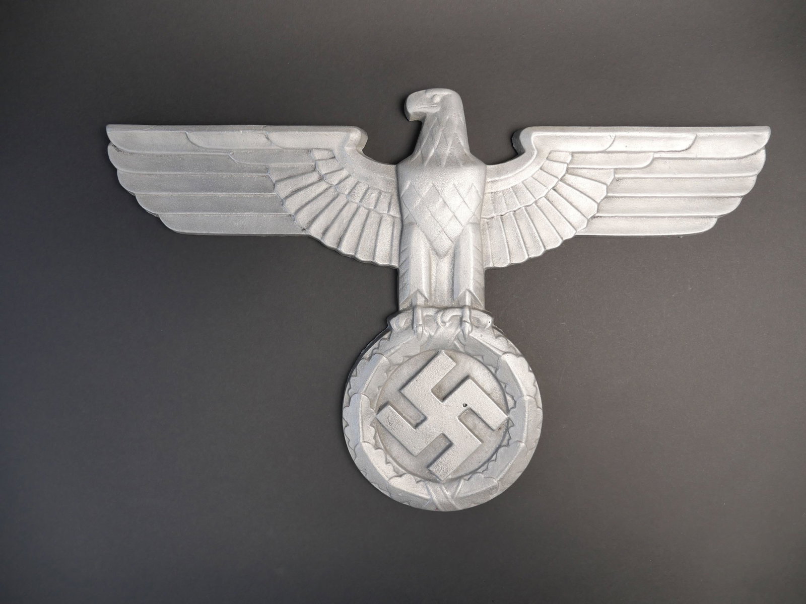 Aigle de facade. Front eagle.: Aigle de facade. En aluminium. Bel aigle en relief. Quatre points d attache au dos de la piece. Fabrication en creux. Sans marquages visibles. Dimensions 39,5 x 35,5 cm. A noter une certaine usure et 