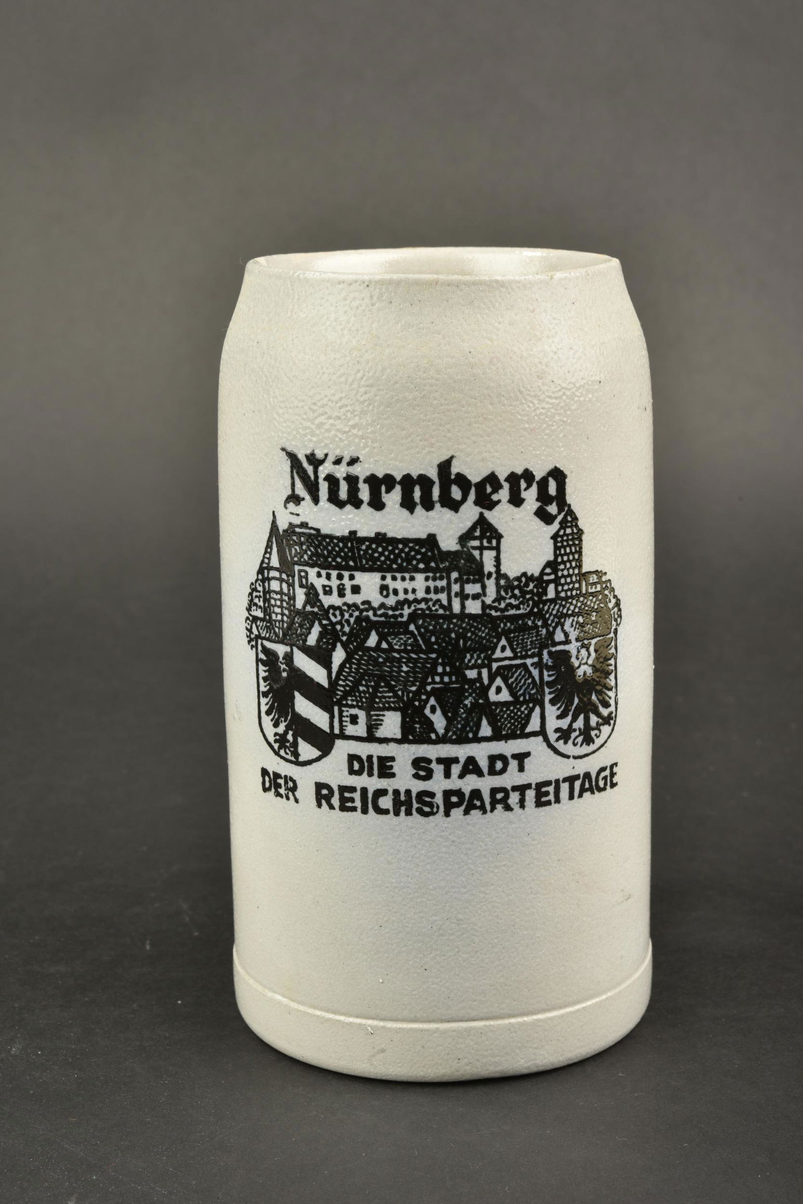 Chope Reichsparteitag. Reichsparteitag mug.: Chope du Reichsparteitag. En gres. Un demi litre. Bien marque Nurnberg Die Stadt der Reichsparteitage. Couvercle manquant. A noter une certaine usure et patine de la piece. Etat II+. Reichsparteitag m