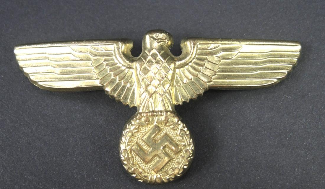 Aigle de coiffure. German cap eagle.: Aigle de coiffure allemande. En metal dore. Tete tournee a gauche. Les attaches sont presentes mais visiblement ressoudees. Fabrication RZM M1/105. A noter une certaine usure et patine de la piece. Et