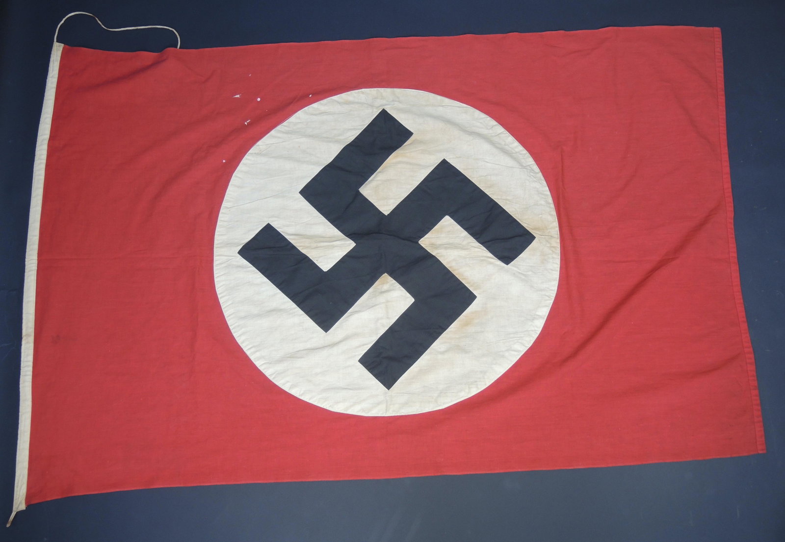 Drapeau allemand. German flag.: Drapeau allemand. En tissu coton rouge. Insigne national imprime et rapporte. Sans marquages visibles. Cordelettes presentes. A noter une certaine usure et patine de la piece, ainsi que des accrocs et