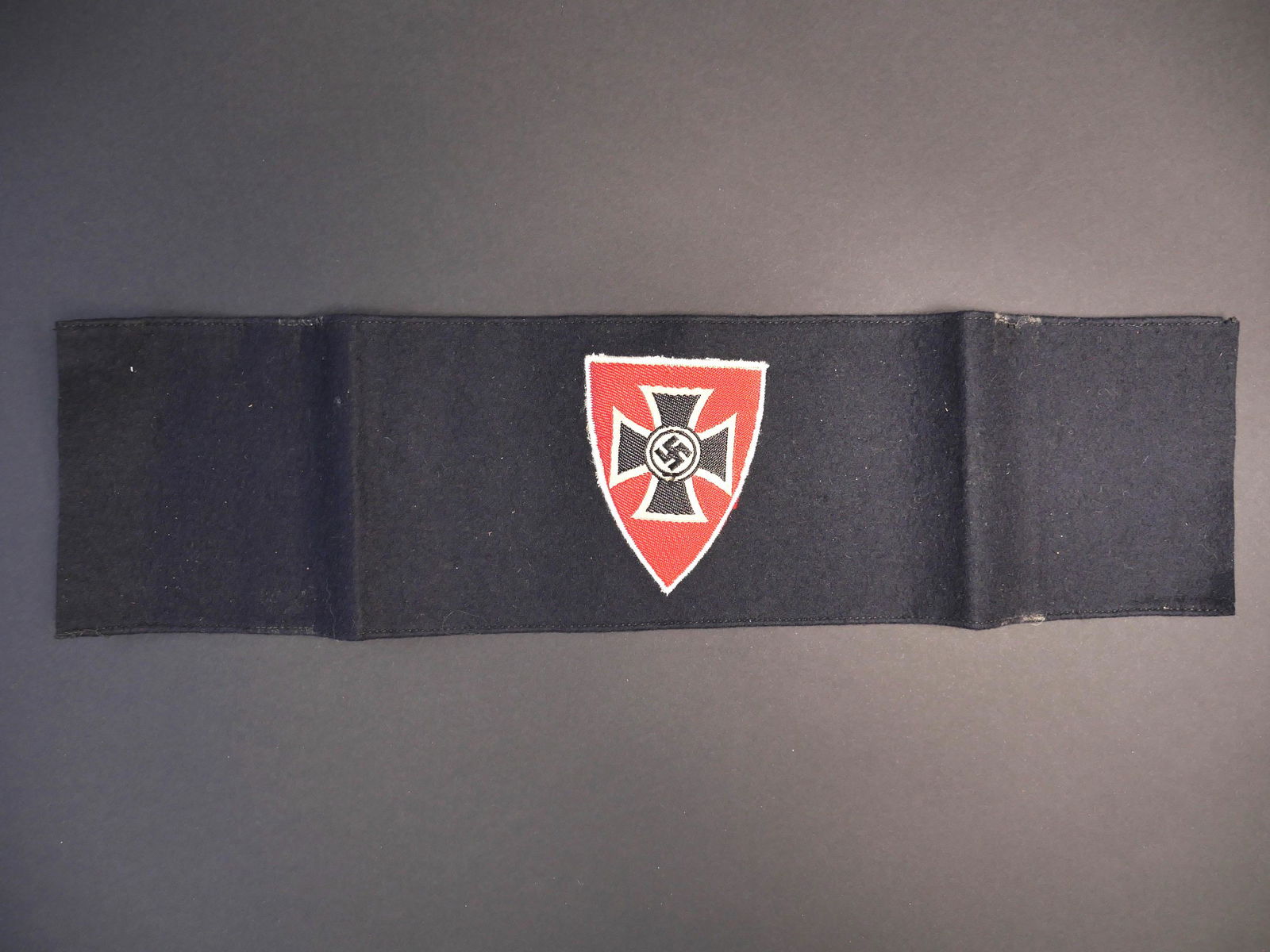 Brassard ancien combattant. Veteran s armband.: Brassard des anciens combattants. En drap de laine bleu marine. Insigne tisse rapporte. Sans marquages visibles. A noter une certaine usure et patine de la piece, ainsi que des trous de mite. Etat II+