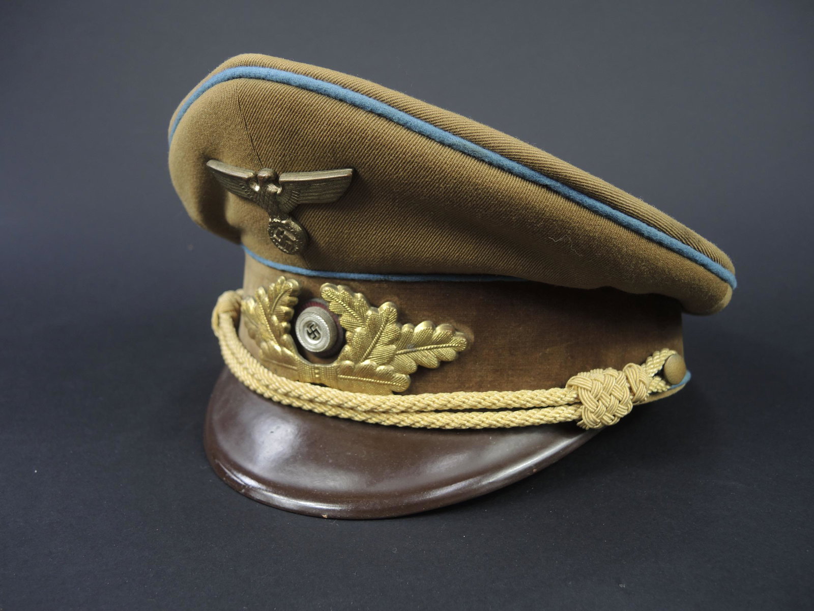 Casquette PL. Politischer Leiter cap.: Casquette Politischer Leiter. En drap marron. Triple lisere bleu. Insignes metalliques dores. Les insignes n ont pas ete demontes afin de verifier les attaches. Fausse jugulaire complete. Interieur do