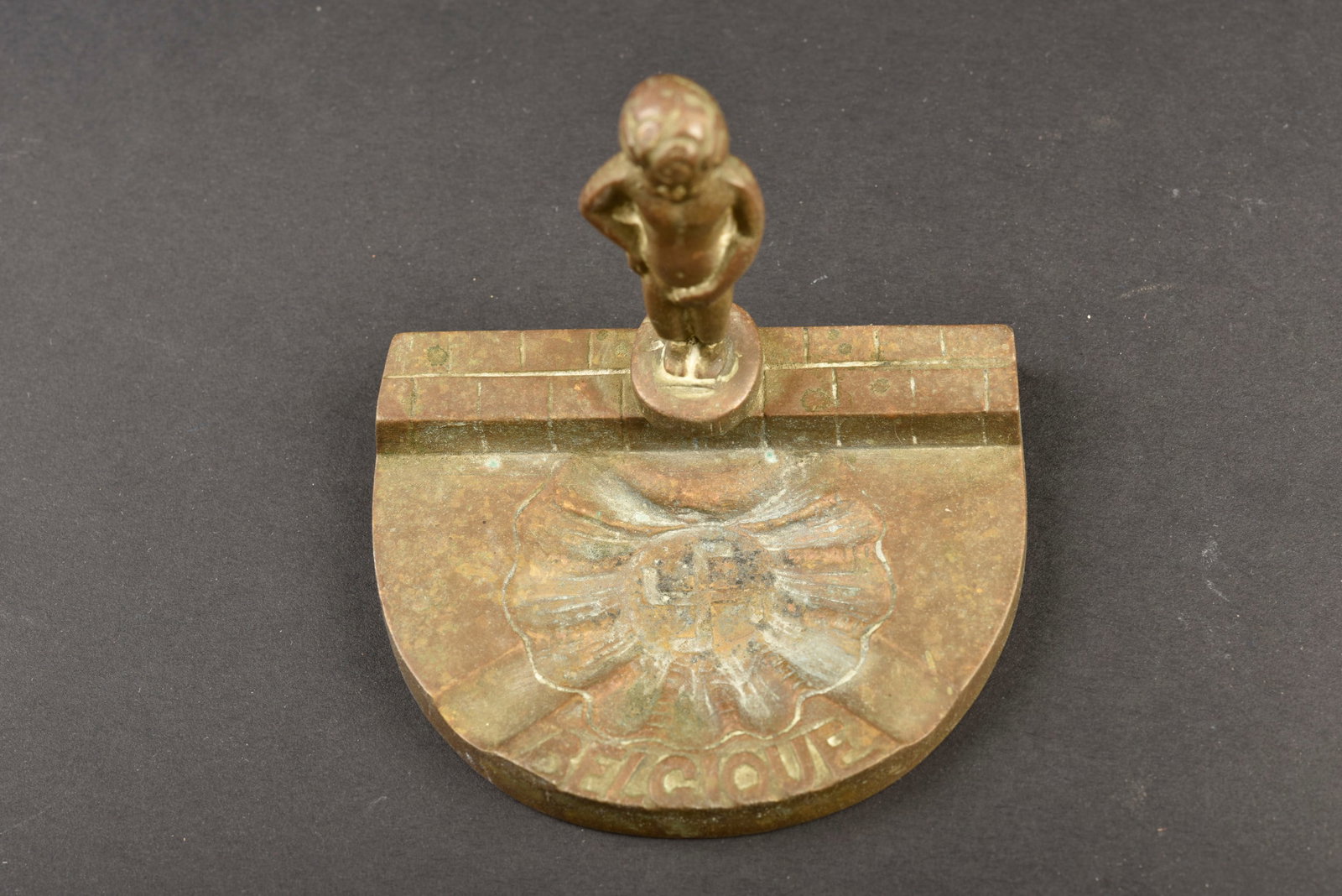 Cendrier anti-nazi. Anti-Nazi ashtray.: Cendrier anti-nazi. En metal representant le Manneken Pis urinant sur le drapeau allemand. Marquage Belgique. Hauteur 7 cm. A noter une certaine usure et patine de la piece. Etat II+. Anti-Nazi ashtra