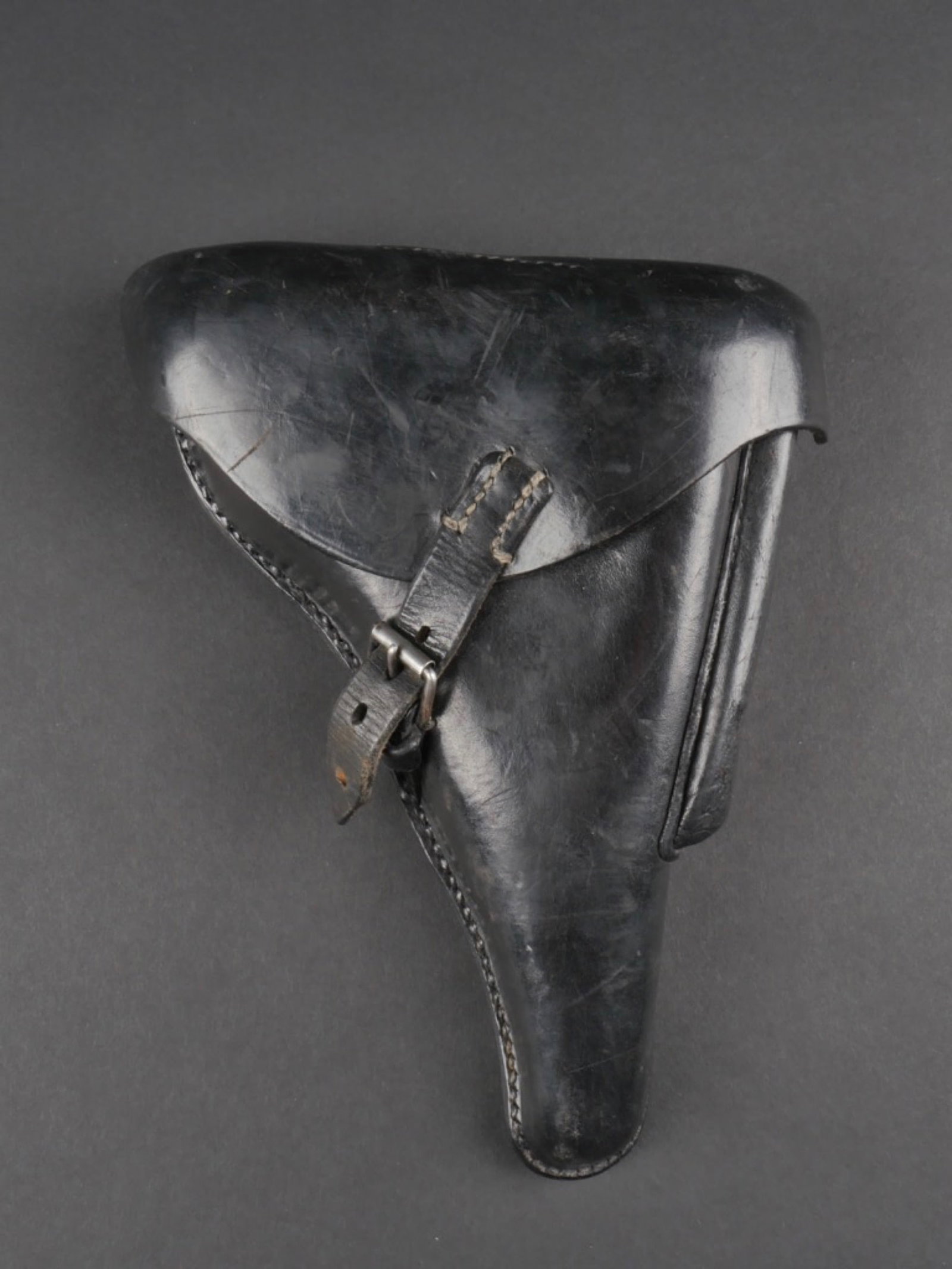 Holster P08. P08 holster.: Holster PO8. En cuir lisse noir. La sangle de fermeture du rabat est complete. La pochette pour outil de demontage est presente. L'outil est absent. Les passants de ceinturon sont complets. Marquages 