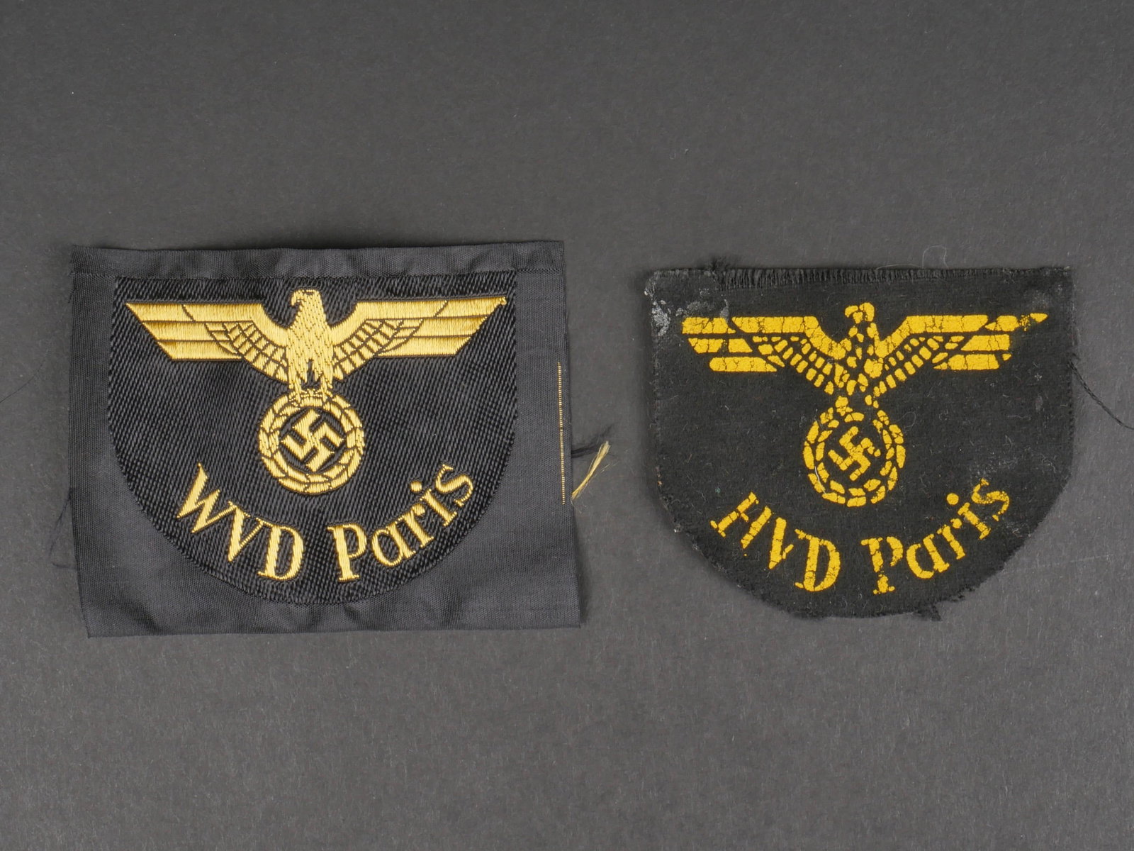 Insignes Reichsbahn Paris. Reichsbahn Paris badges.: Insignes Reichsbahn Paris. Comprenant un insigne WVD Paris, Bevo, jamais monte, traces de colle au dos. Un rare insigne HVD Paris, aigle et mention HVD Paris imprimees sur fond en drap noir, visibleme