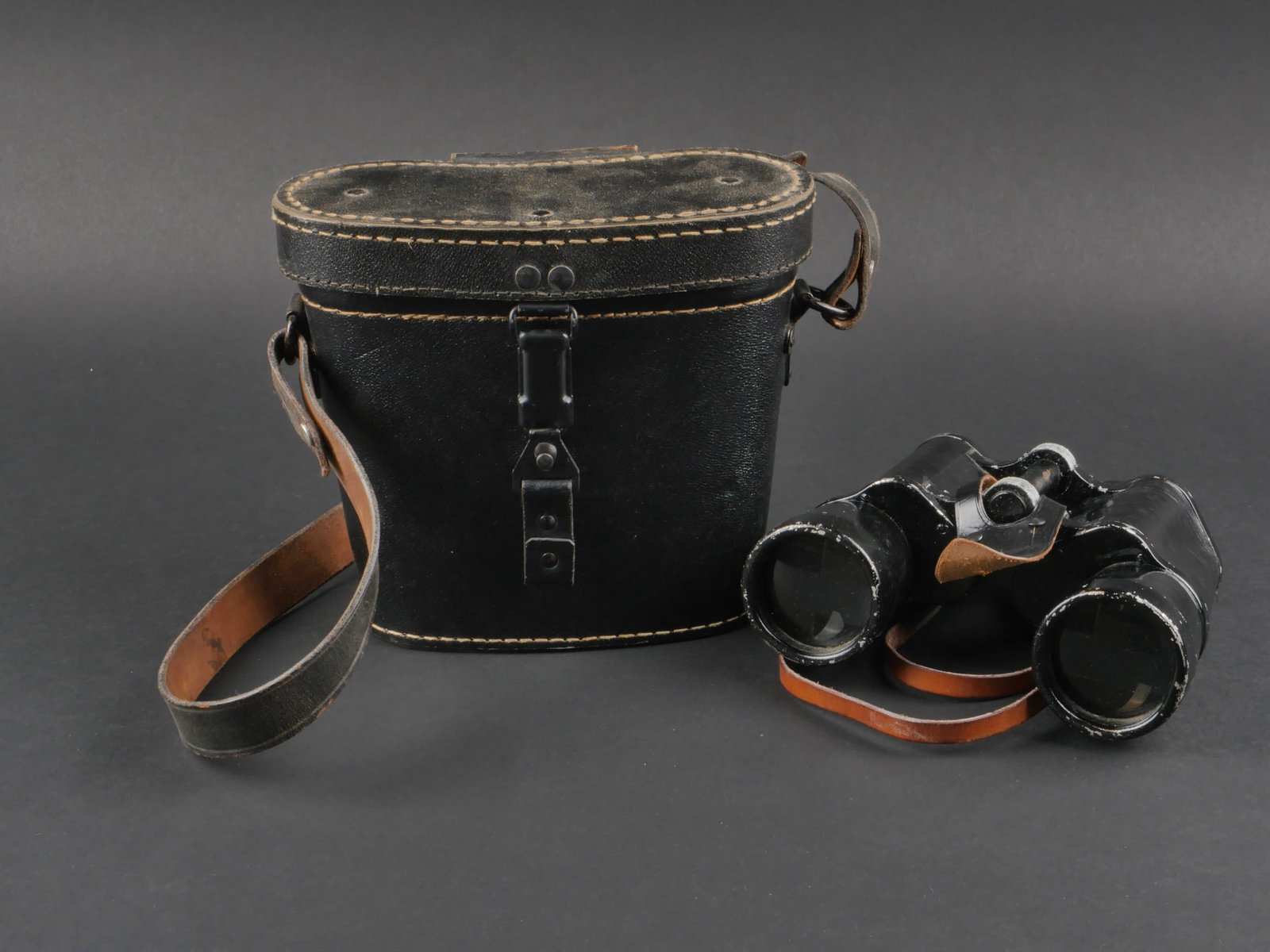 Jumelles 10 x 50. 10 x 50 binoculars.: Jumelles 10 x 50. Revetement de couleur noir, en relativement bon etat. Beau marquages Dienstglas 10x50 5348 BLC. Optiques claires et graduees presentant quelques taches. Courroie en cuir marron prese