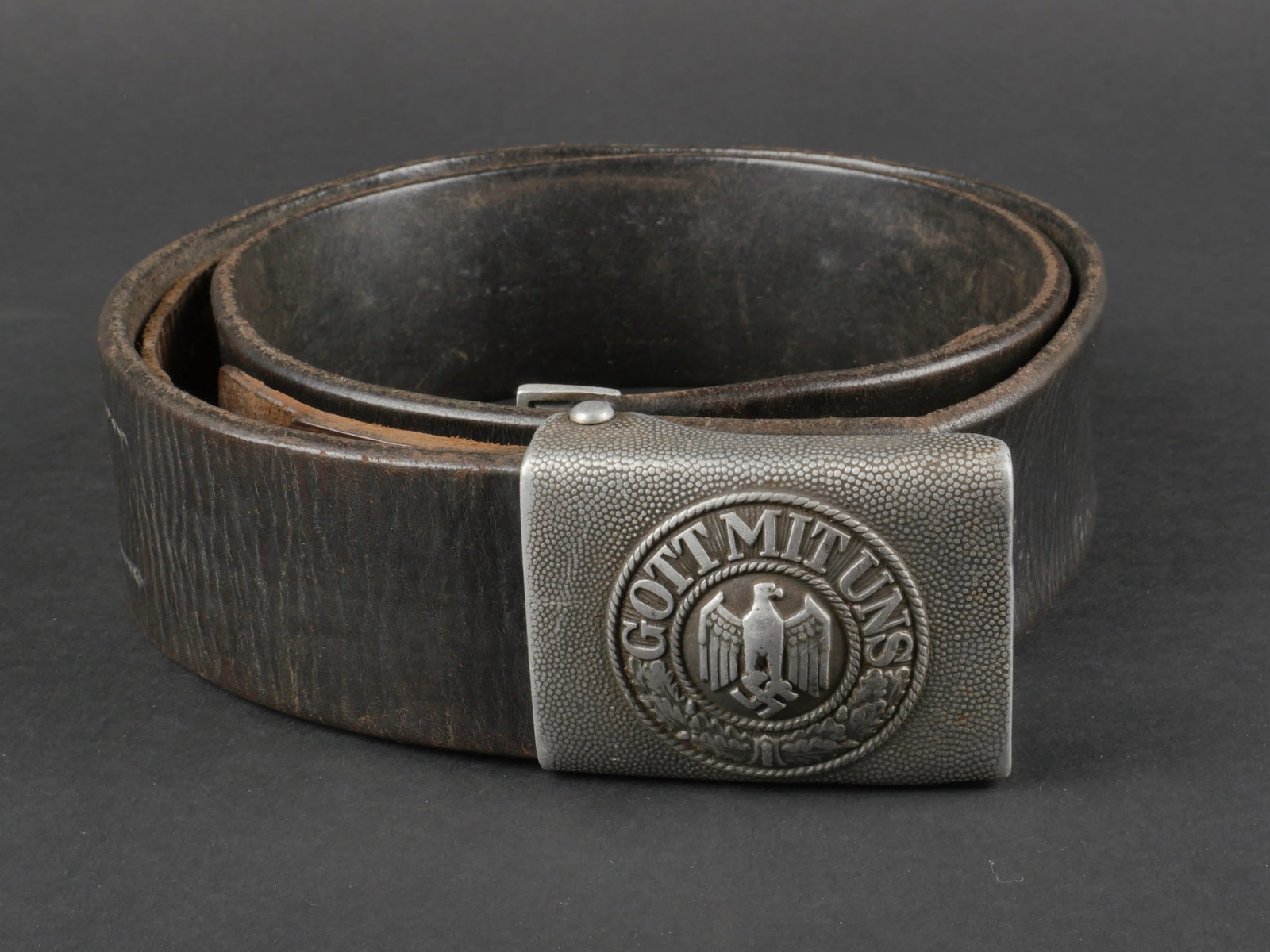Ceinturon de la Heer. Heer belt.: Ceinturon de la Heer. En cuir noir lisse. Modele disposant d'une patte de reglage en cuir. Bouclerie en metal. Sans marquages visibles. Boucle de ceinturon en aluminium grenele, sans marquages visible