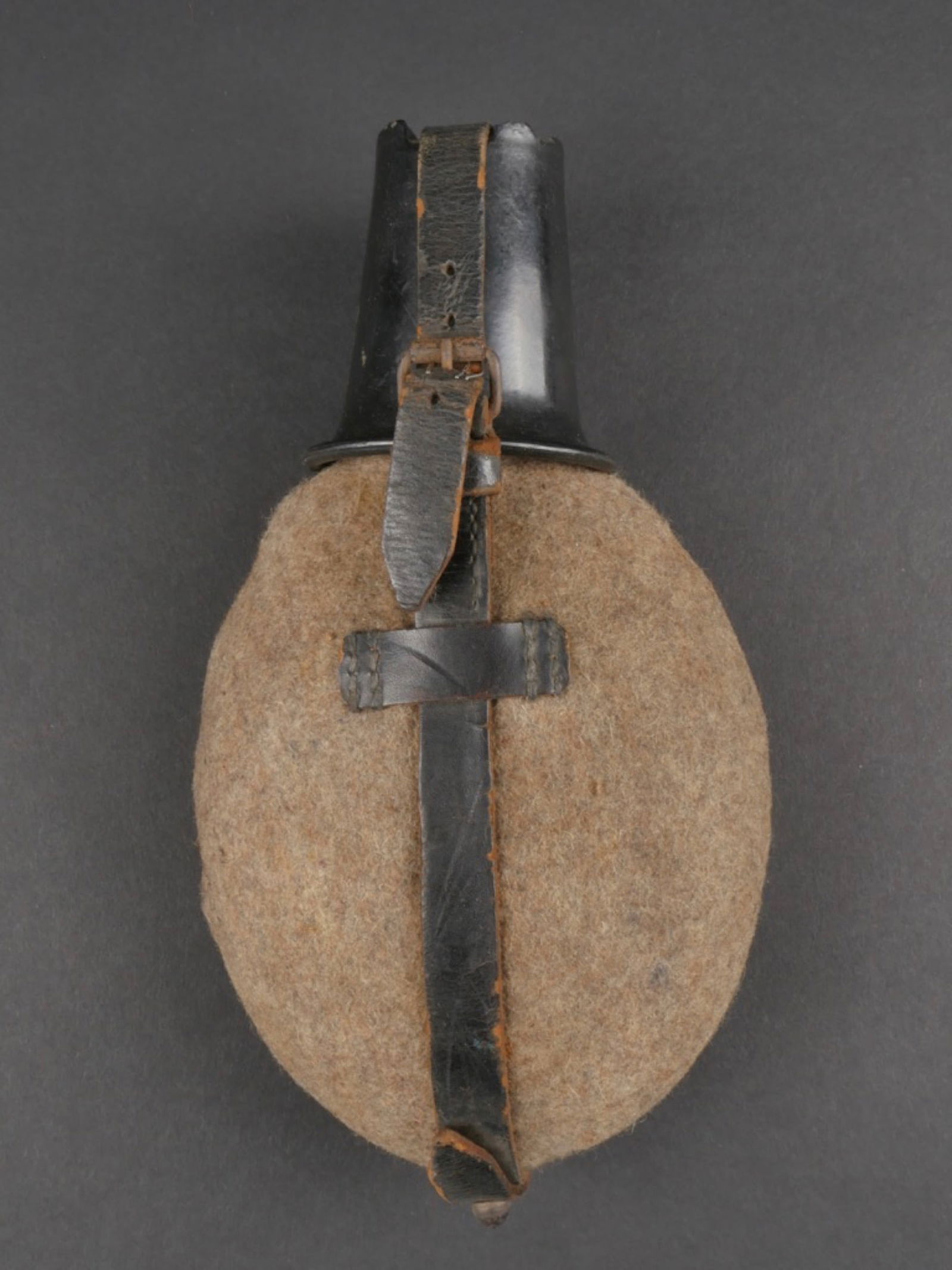 Gourde allemande.: Gourde allemande. En metal emaille rouge. Bouchon en bakelite. Harnais en cuir complet avec son mousqueton fonctionnel. Un morceau de cuir est casse et recolle. Housse en feutrine Feldgrau, tous les b