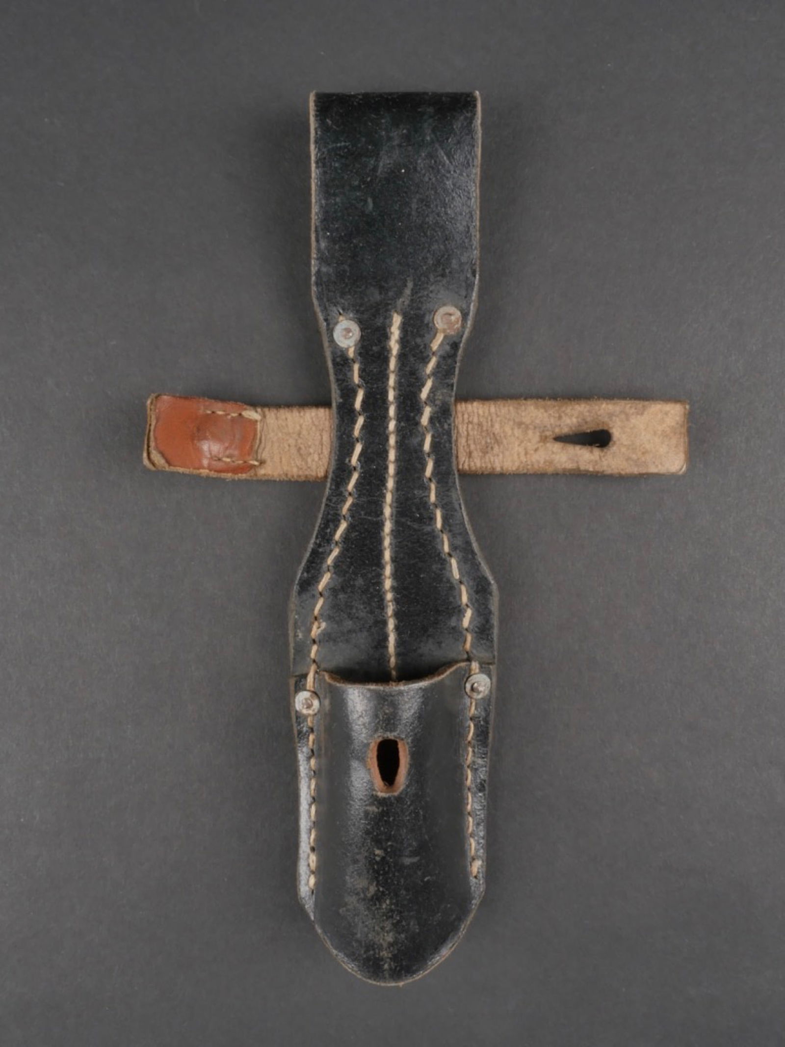 Gousset de baionnette. Bayonet gusset.: Gousset de baionnette. En cuir noir, modele avec attache. Cuir souple. Marquages RBNr 0/0566/0015. A noter une certaine usure et patine de la piece. Etat II+. Bayonet gusset. In black leather, model w