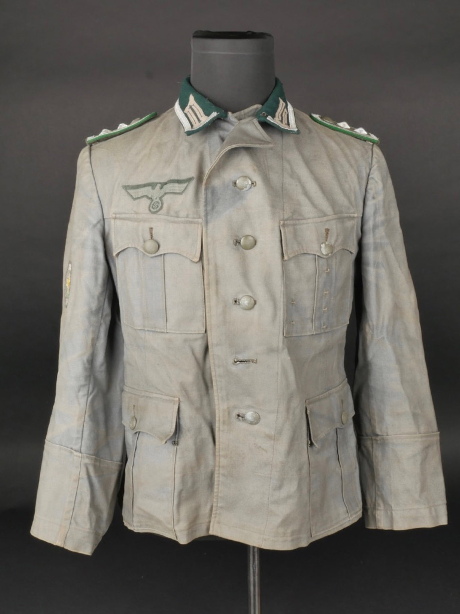 Vareuse Gebirgsjager. Gebirgsjager jacket.: Vareuse de sous-officier des Gebirgsjager. En tissu coton Feldgrau, fortement delave par le soleil. Vol vert canard. Galon argent faisant le tour du col. Litzen montes main. Tous les boutons sont pres