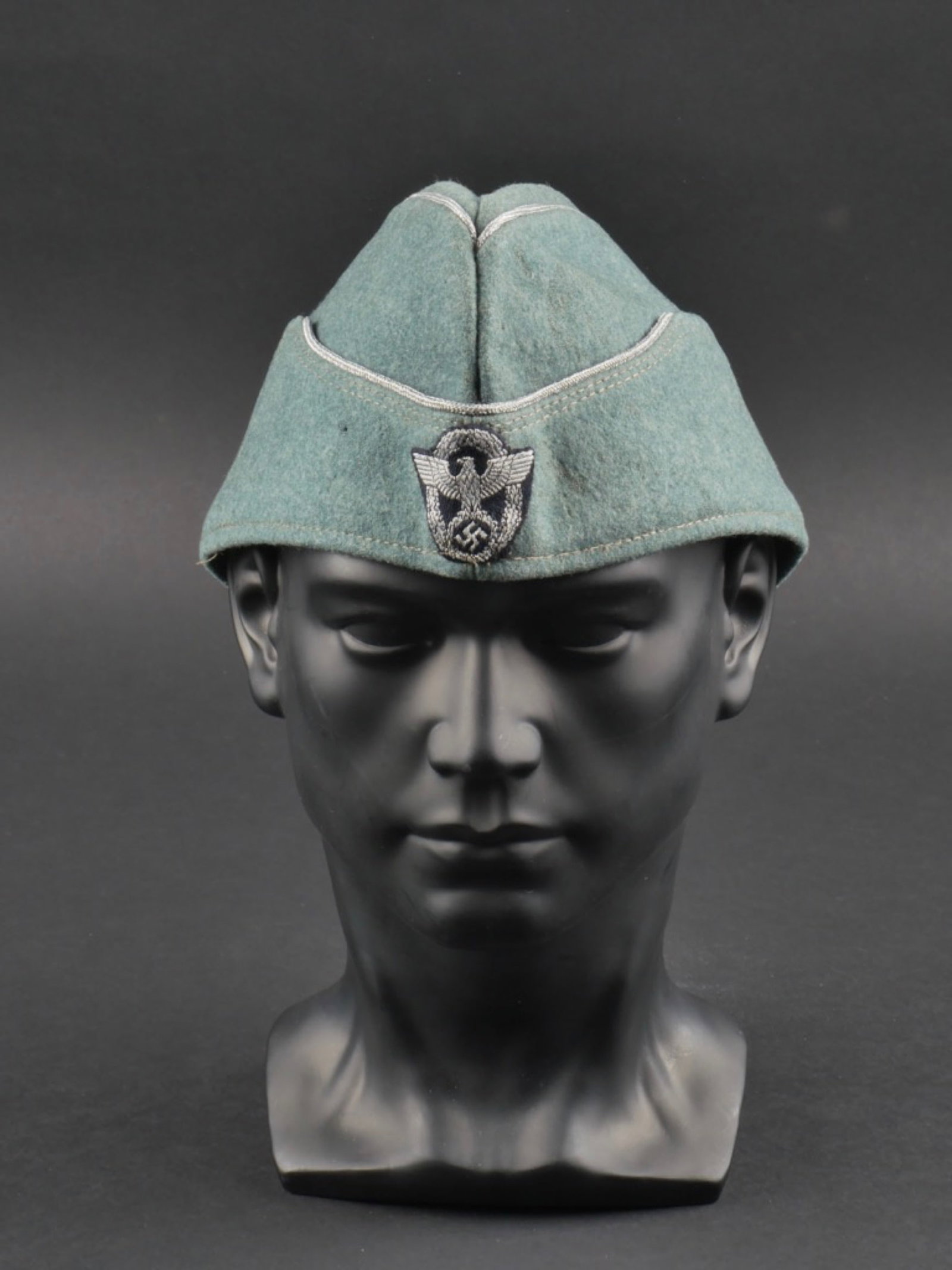 Calot officier Polizei. Polizei officer cap.: Calot d'officier Polizei. En drap gris/vert. Lisere argent faisant le tour de la coiffure. Insigne Polizei monte main. Interieur double en satinette verte. Demi bandeau de sudation partiellement decou