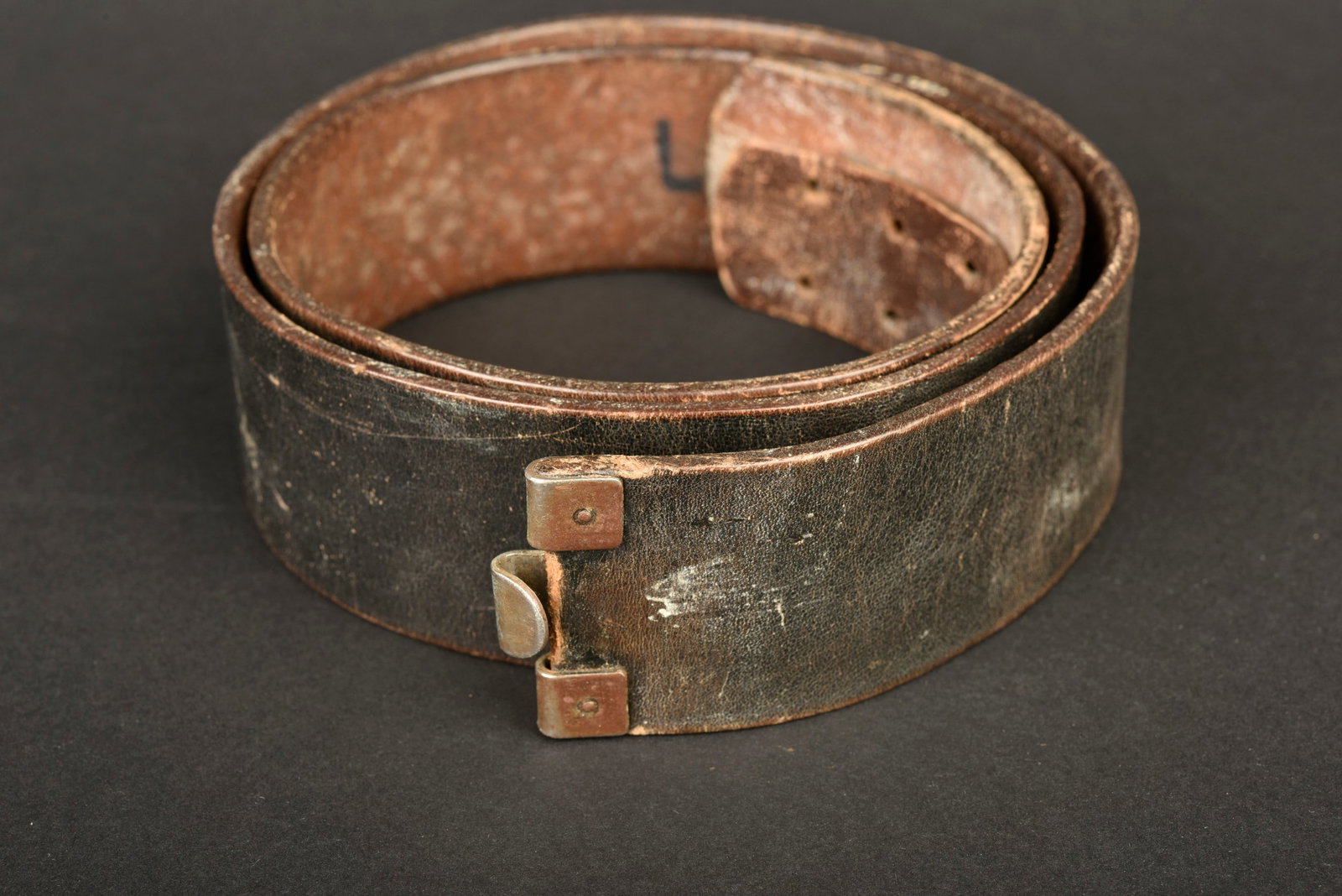 Cuir de ceinturon. Belt leather.: Cuir de ceinturon allemand. En cuir noir. Bouclerie en metal. Patte de reglage presente, complete, probablement recousue. Taille 100. Indication nominative illisible. A noter une certaine usure et pat